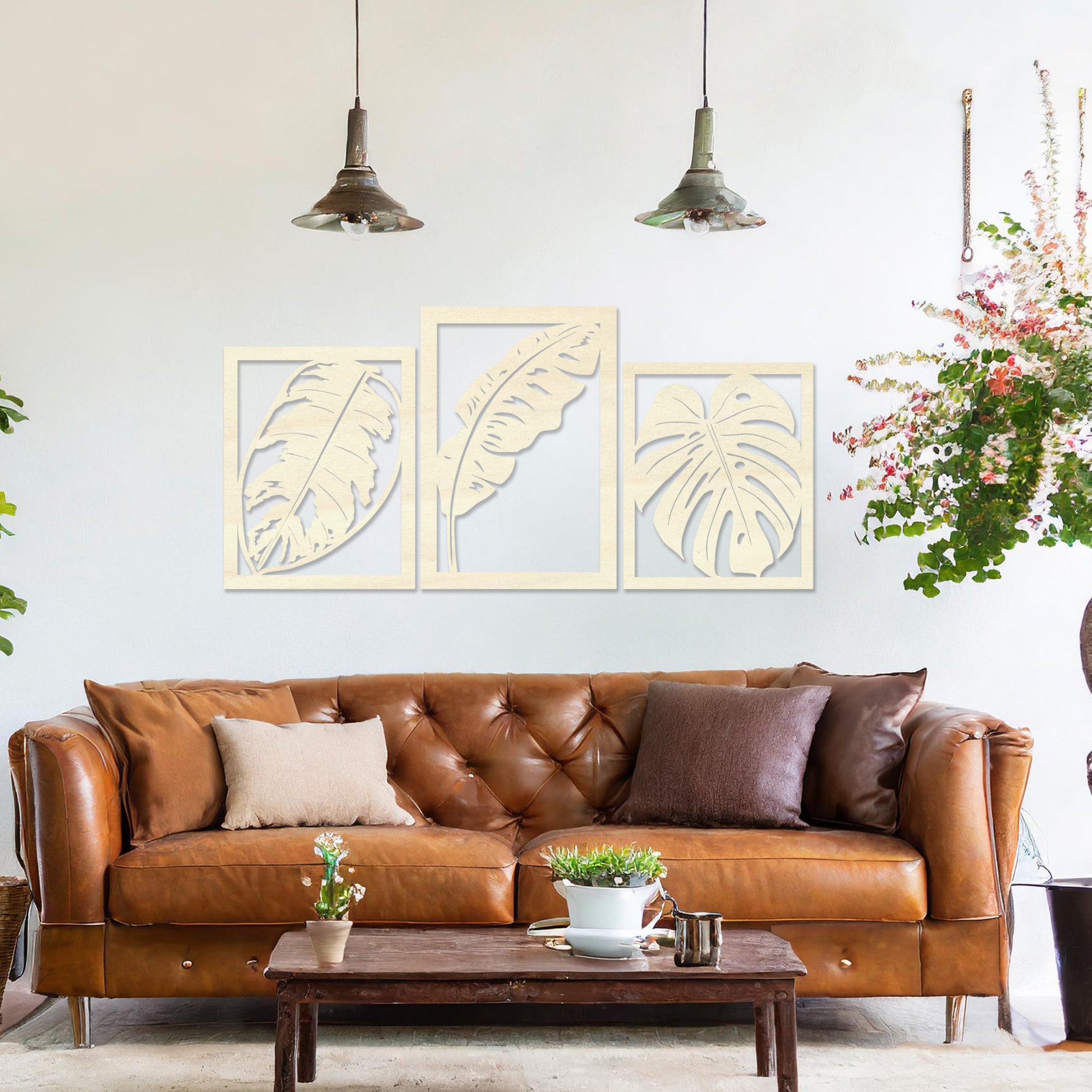 A three-piece wall art set featuring artistic depictions of tropical leaves, including monstera and banana leaves, framed in a rectangular layout. The artwork is displayed on a neutral wall in a modern room