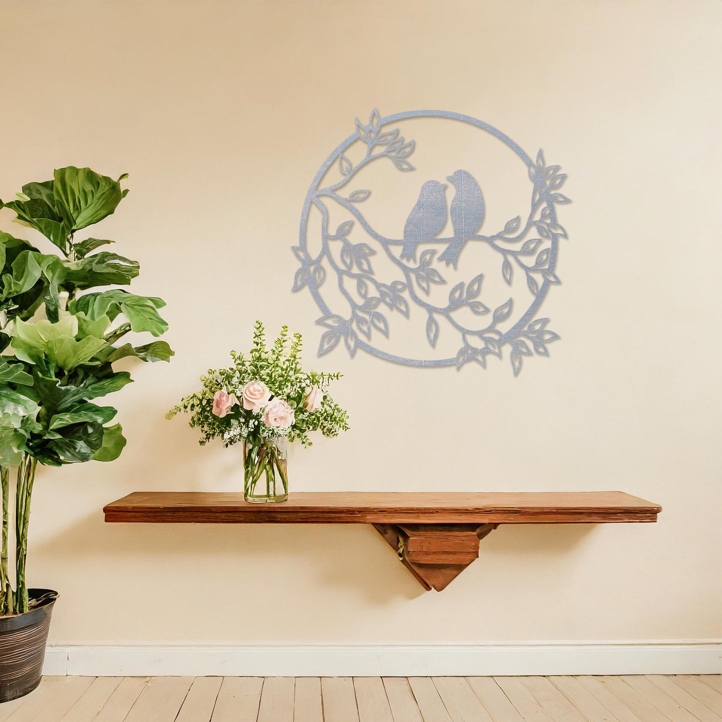 Wooden wall art featuring a circular design with two birds perched on a branch surrounded by leaves, displayed on a neutral wall within modern room decor, showcasing its delicate and nature-inspired craftsmanship.