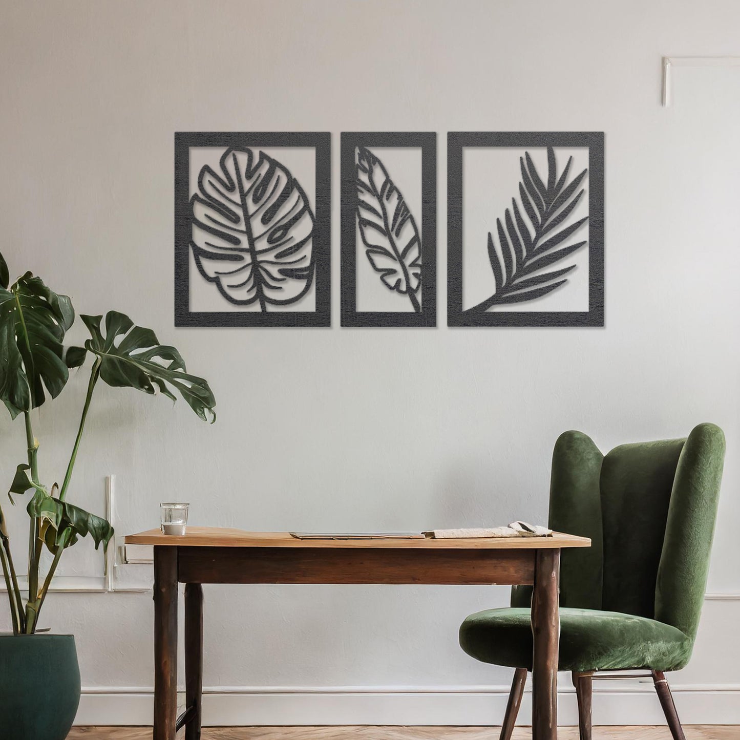 Wooden wall art set featuring three framed botanical designs with detailed leaf patterns, including monstera and palm leaves. The artwork is displayed on a neutral wall within modern room decor, adding a natural and elegant touch.