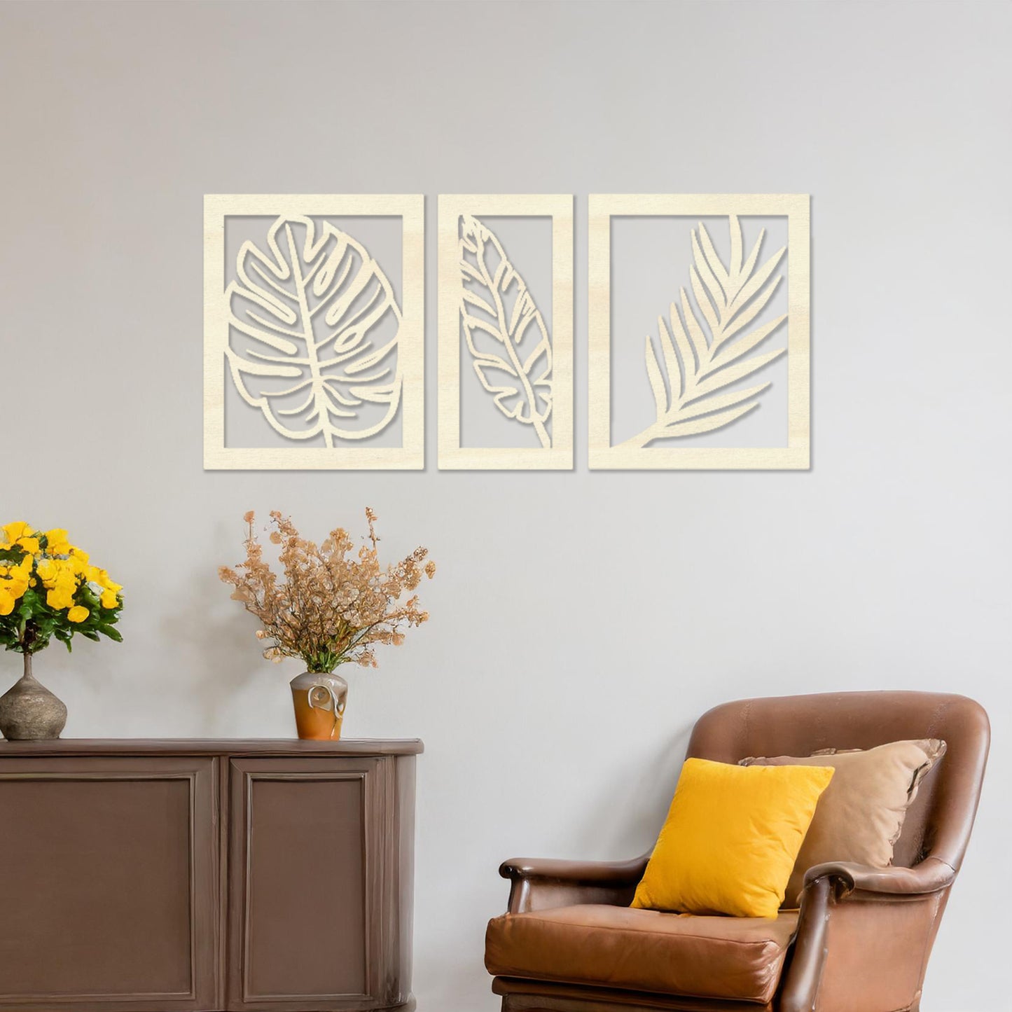 Wooden wall art set featuring three framed botanical designs with detailed leaf patterns, including monstera and palm leaves. The artwork is displayed on a neutral wall within modern room decor, adding a natural and elegant touch.