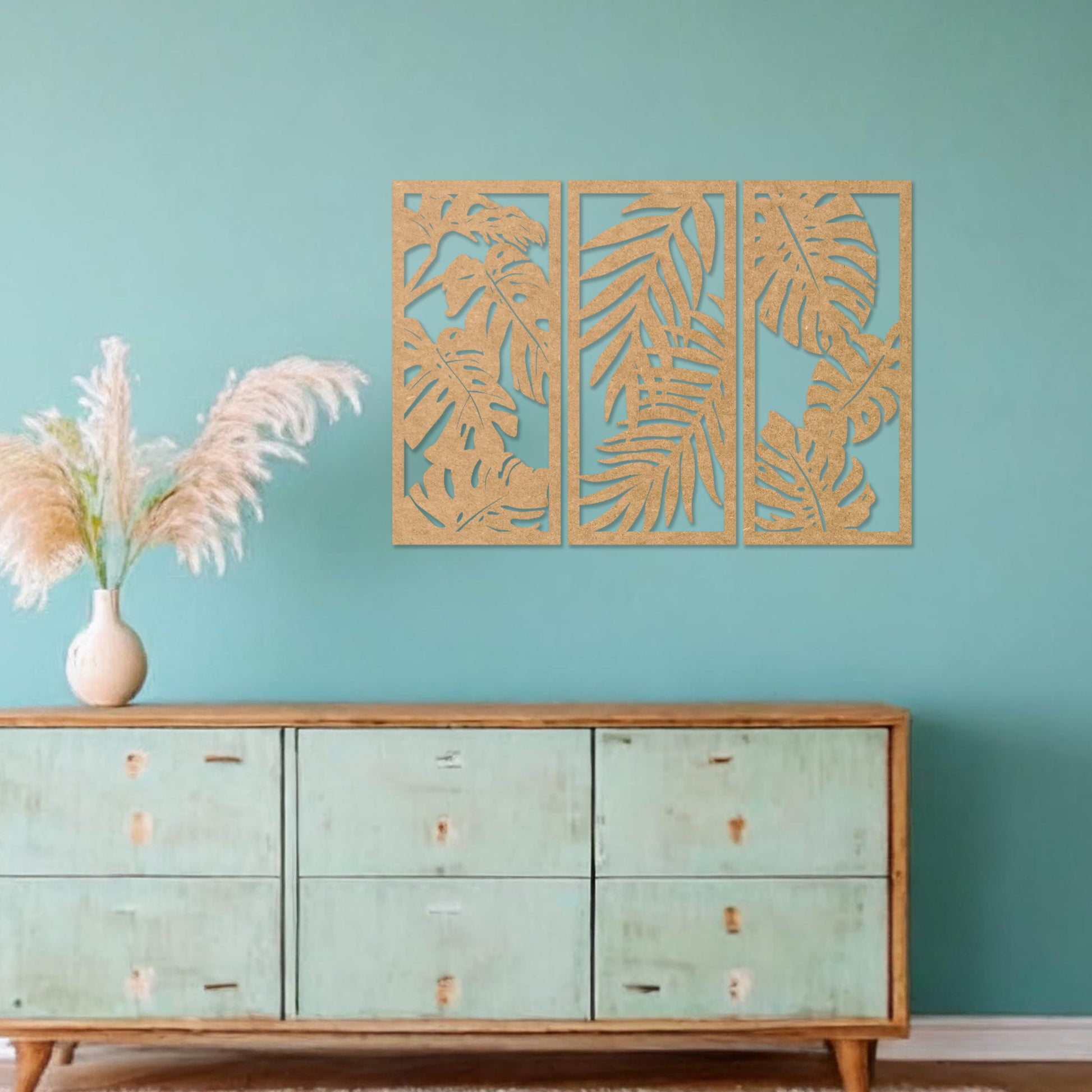 A set of three wooden wall panels featuring intricate tropical leaf designs, creating a cohesive and elegant decorative piece. Displayed on a neutral wall within modern room decor, this artwork brings a touch of nature indoors.