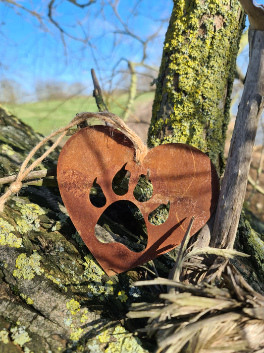 This heart-shaped metal ornament features a cat paw silhouette, symbolising love for feline companions. Its rustic finish adds a natural charm, and it includes a jute twine for easy hanging. Ideal for cat lovers and rustic-themed decor.
