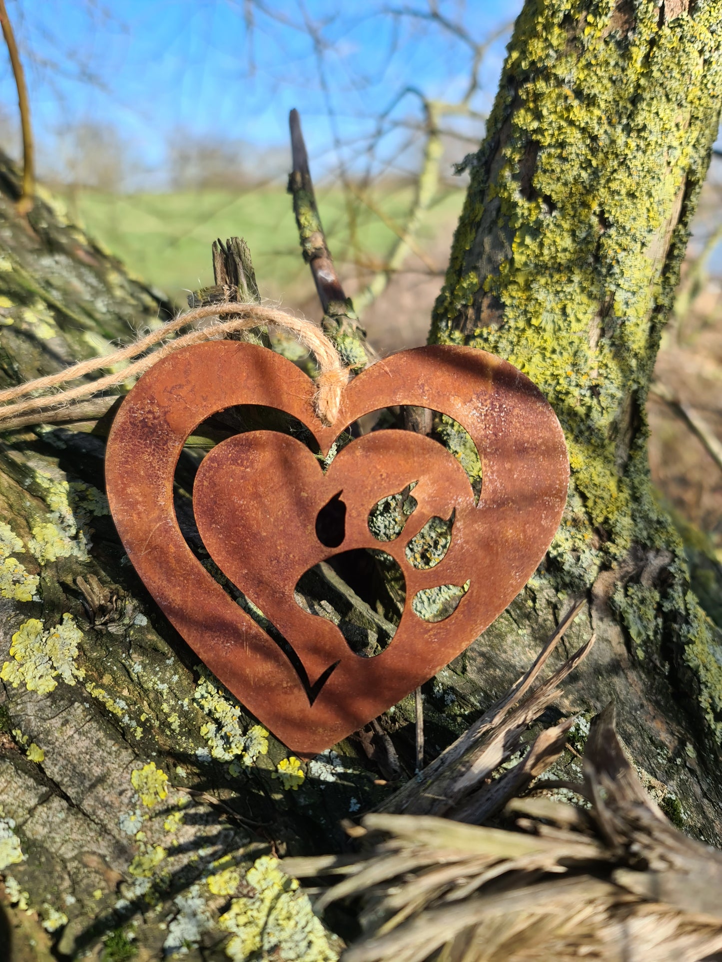 This heart-shaped metal ornament features a delicate cut-out design of a cat paw within a layered heart. With its rustic finish and jute twine for hanging, it’s perfect for cat lovers and adds a touch of warmth to any decor.