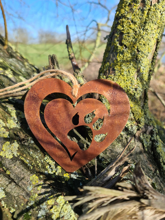This heart-shaped metal ornament features a delicate cut-out design of a cat paw within a layered heart. With its rustic finish and jute twine for hanging, it’s perfect for cat lovers and adds a touch of warmth to any decor.