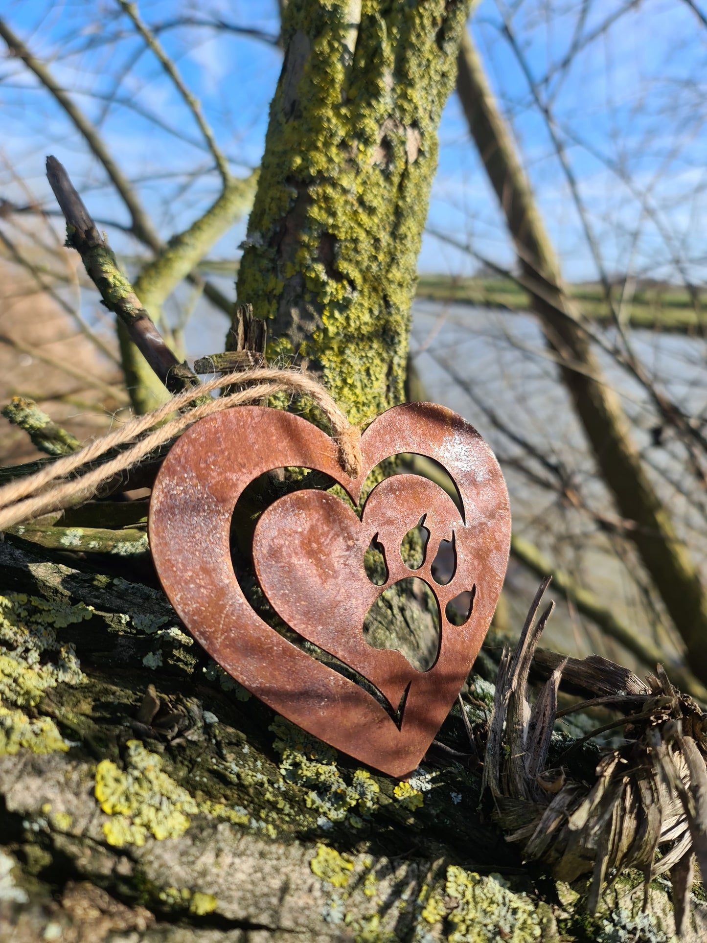 This heart-shaped metal ornament features a delicate cut-out design of a cat paw within a layered heart. With its rustic finish and jute twine for hanging, it’s perfect for cat lovers and adds a touch of warmth to any decor.