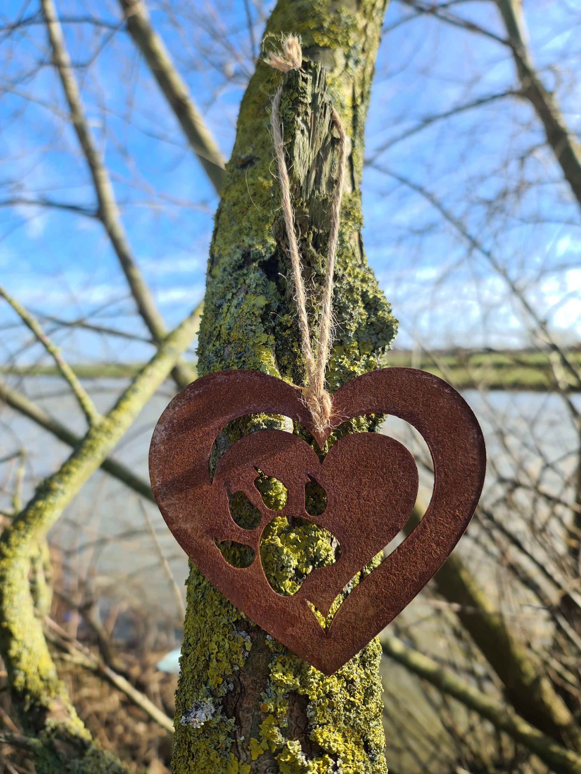 This heart-shaped metal ornament features a delicate cut-out design of a cat paw within a layered heart. With its rustic finish and jute twine for hanging, it’s perfect for cat lovers and adds a touch of warmth to any decor.