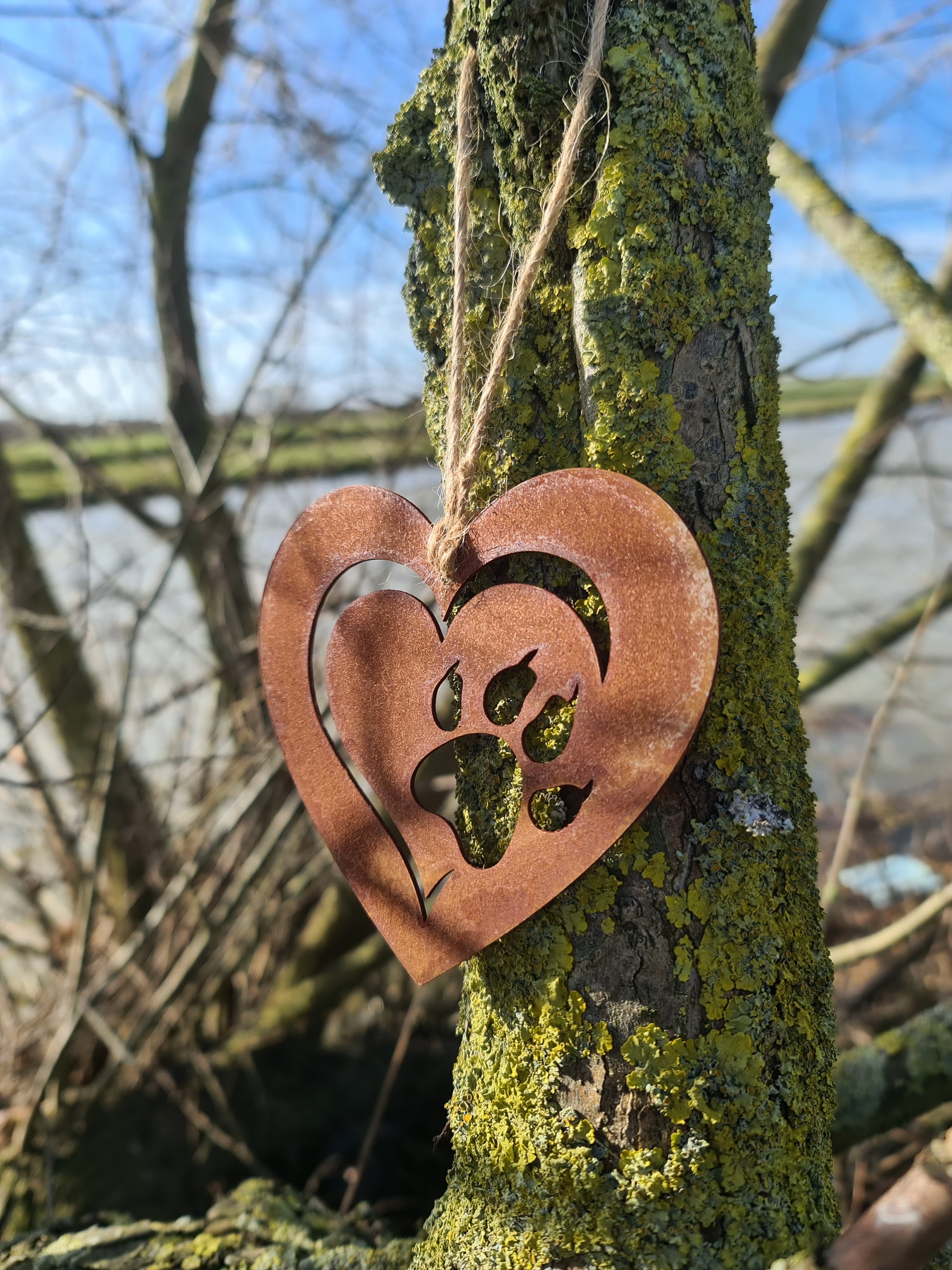 This heart-shaped metal ornament features a delicate cut-out design of a cat paw within a layered heart. With its rustic finish and jute twine for hanging, it’s perfect for cat lovers and adds a touch of warmth to any decor.
