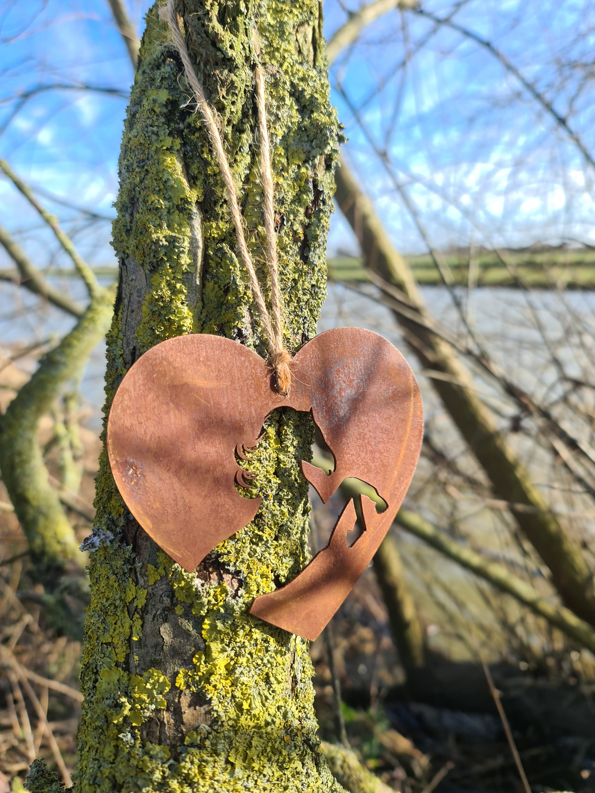 This heart-shaped metal ornament features a beautifully cut horse silhouette within the heart's frame. The rustic, weathered finish adds a natural and charming aesthetic. Complete with a jute twine for hanging, it's perfect for countryside or horse-themed decor.