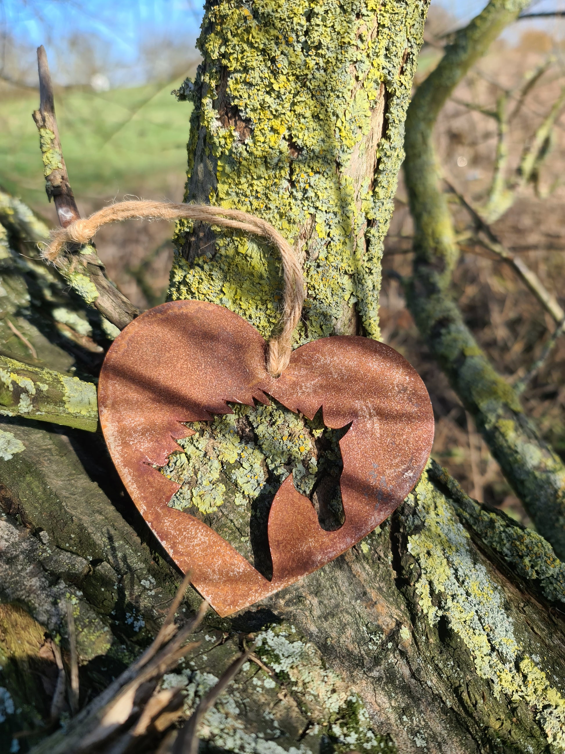 This rustic heart-shaped ornament features a detailed silhouette of a horse's head cut out in the center. The weathered, rusted finish adds a natural charm, while the jute twine provides a simple yet elegant way to hang it. Perfect for outdoor or rustic-themed decor.