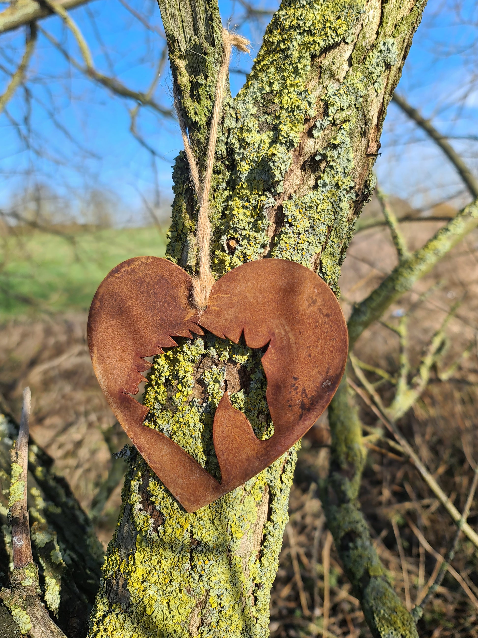 This rustic heart-shaped ornament features a detailed silhouette of a horse's head cut out in the center. The weathered, rusted finish adds a natural charm, while the jute twine provides a simple yet elegant way to hang it. Perfect for outdoor or rustic-themed decor.