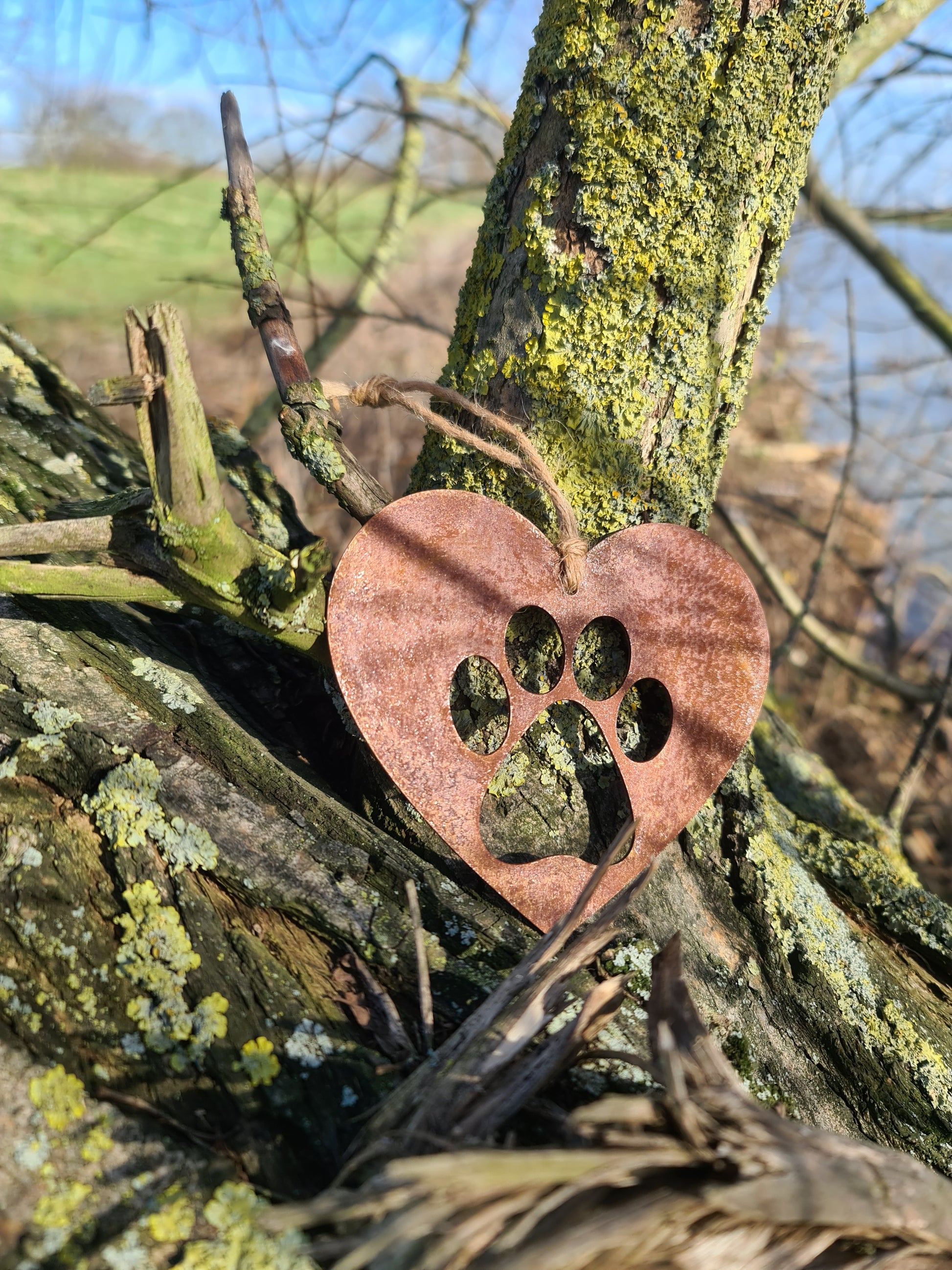 This is a heart-shaped metal decoration featuring a dog's paw print cut-out. Crafted with a rustic finish, this piece makes a thoughtful gift for dog lovers or a charming addition to any home or garden decor, celebrating the bond with a beloved pet.