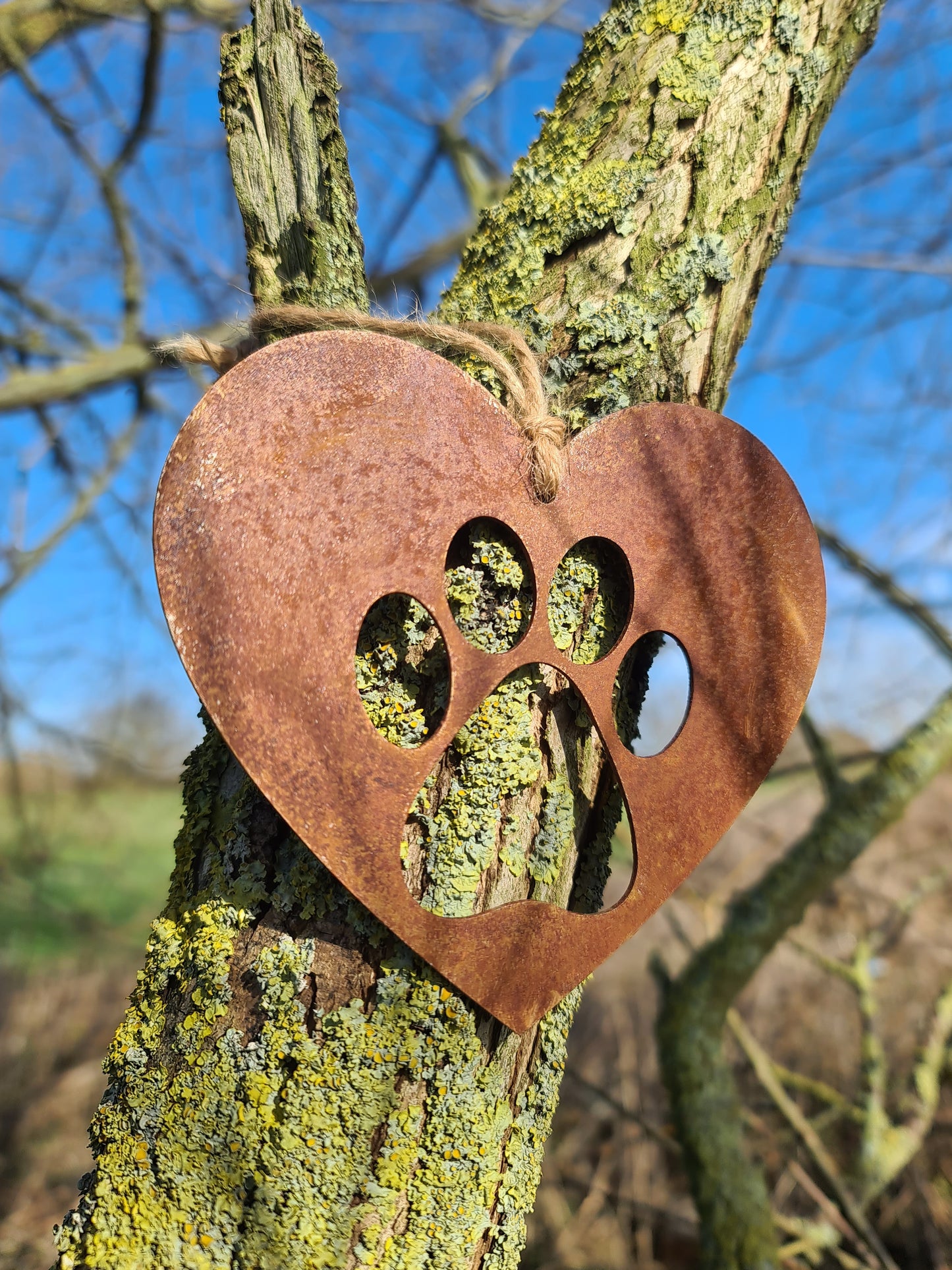 This is a heart-shaped metal decoration featuring a dog's paw print cut-out. Crafted with a rustic finish, this piece makes a thoughtful gift for dog lovers or a charming addition to any home or garden decor, celebrating the bond with a beloved pet.