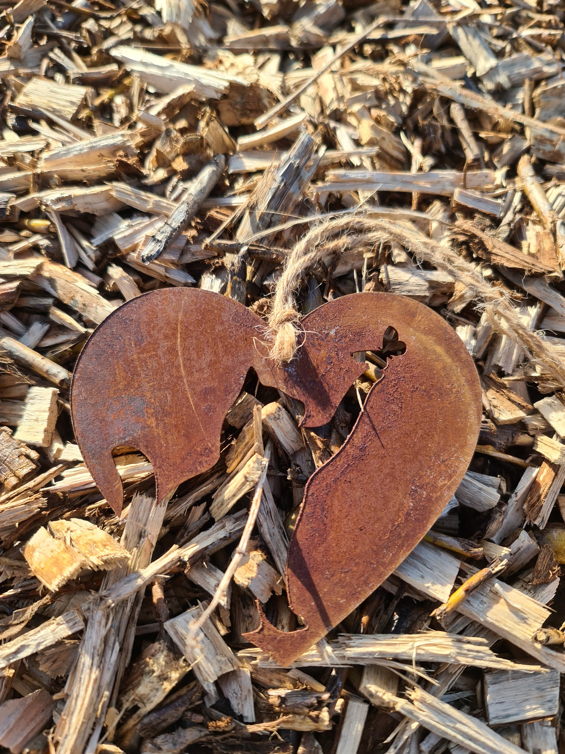 This heart-shaped metal ornament showcases a rustic cut-out silhouette of a cat, elegantly crafted for feline lovers. Its natural weathered finish and jute twine hanger make it a charming addition to any indoor or outdoor decor.