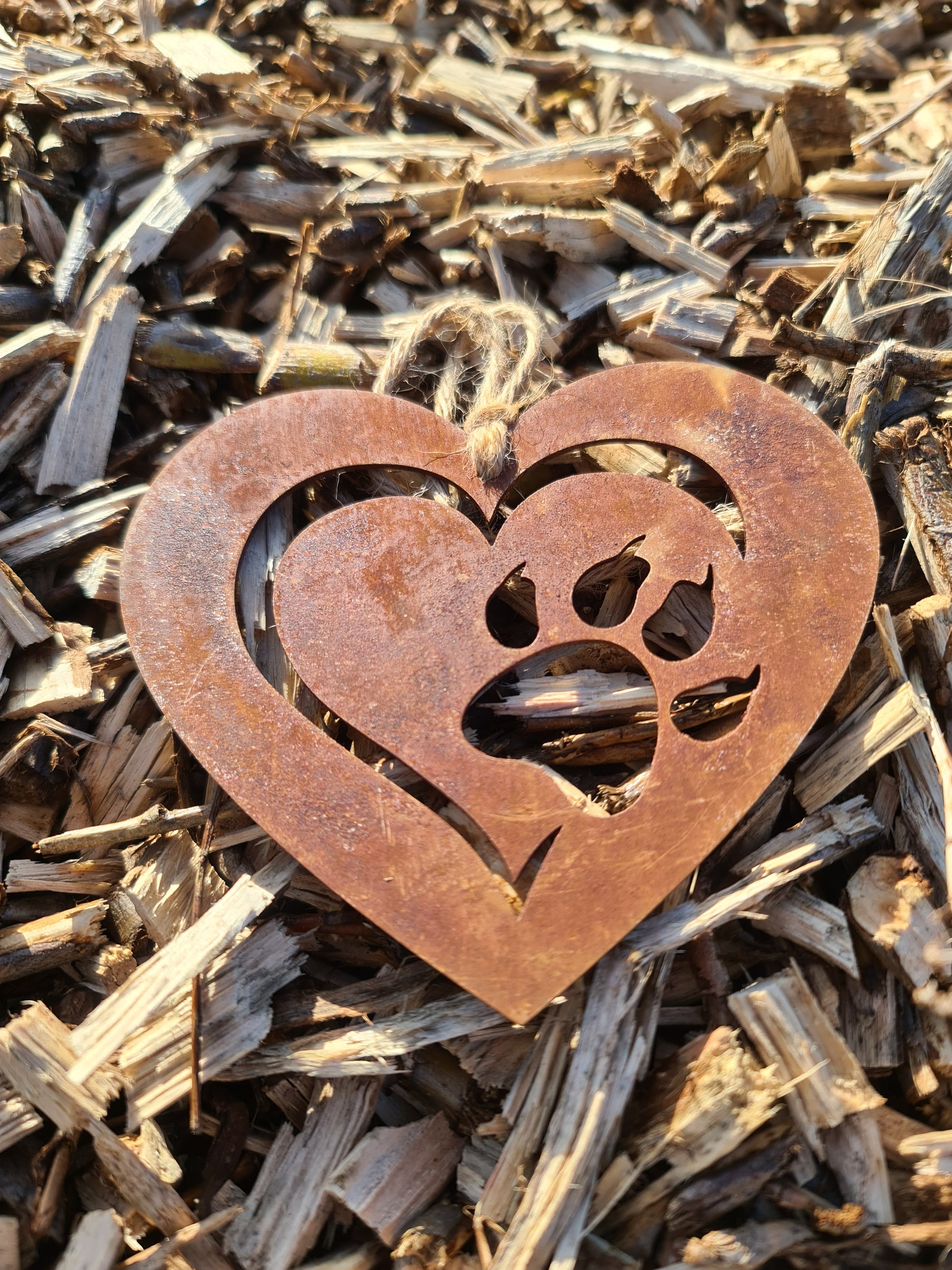This heart-shaped metal ornament features a delicate cut-out design of a cat paw within a layered heart. With its rustic finish and jute twine for hanging, it’s perfect for cat lovers and adds a touch of warmth to any decor.