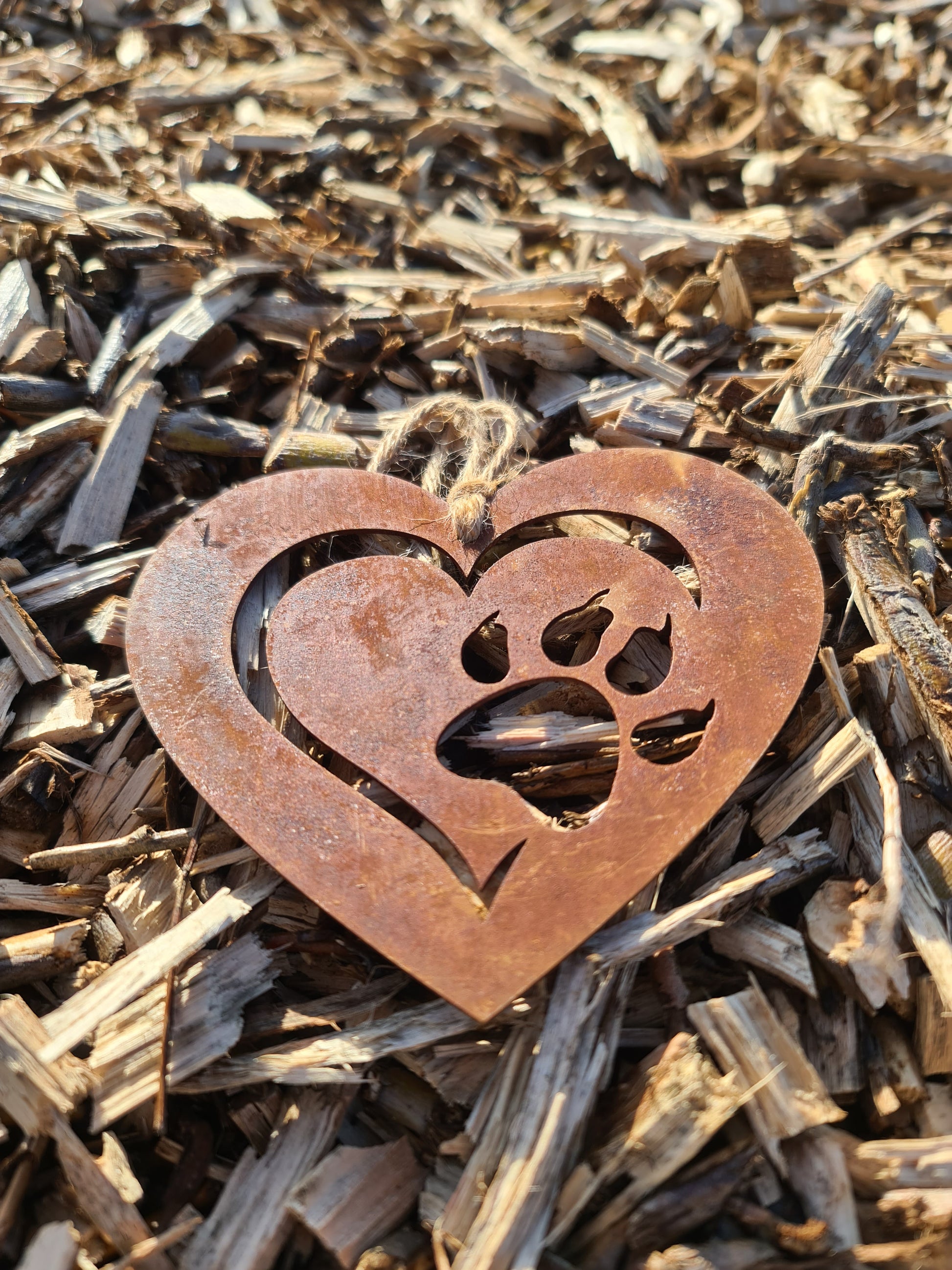 This heart-shaped metal ornament features a delicate cut-out design of a cat paw within a layered heart. With its rustic finish and jute twine for hanging, it’s perfect for cat lovers and adds a touch of warmth to any decor.