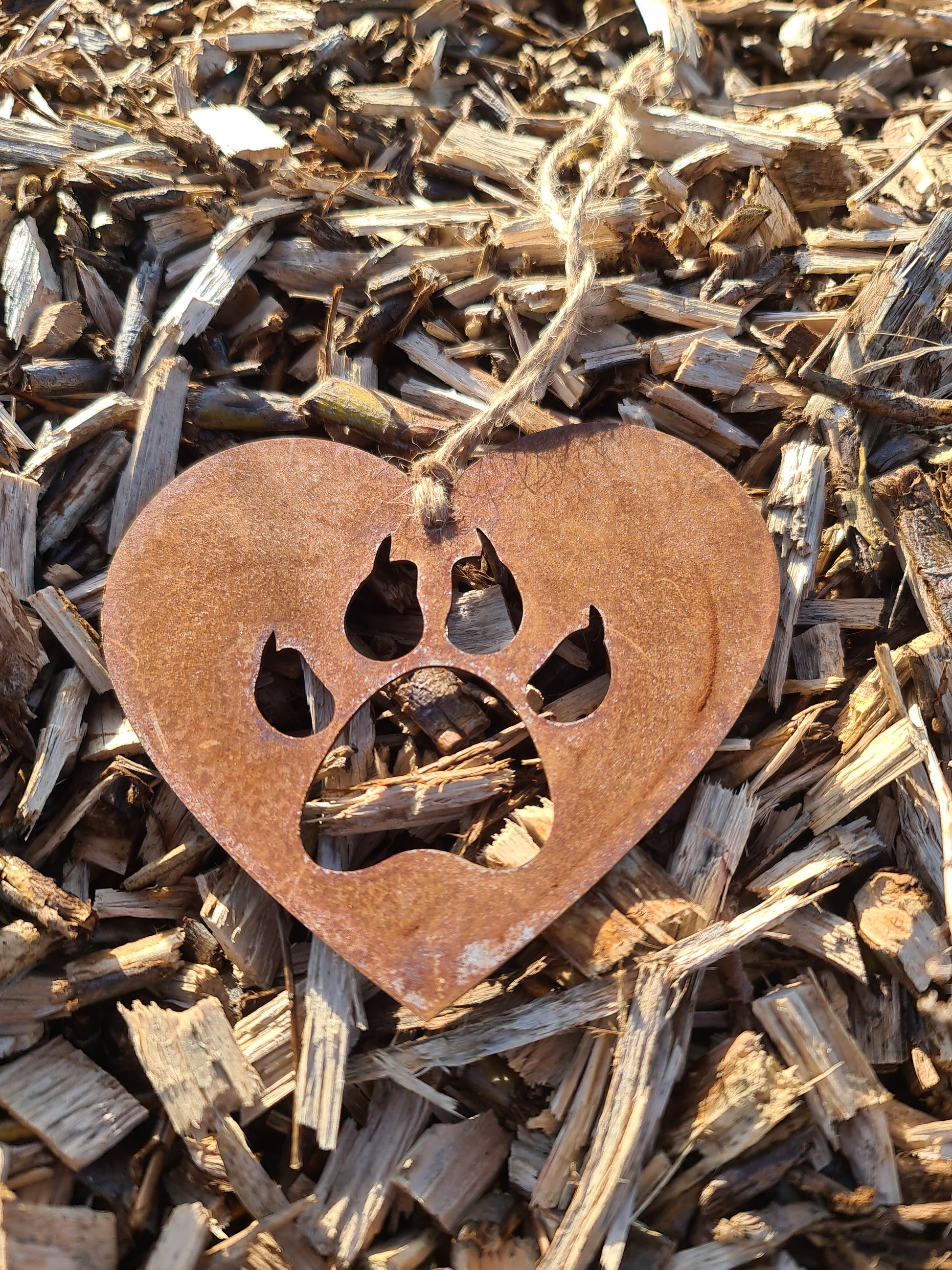 This heart-shaped metal ornament features a cat paw silhouette, symbolising love for feline companions. Its rustic finish adds a natural charm, and it includes a jute twine for easy hanging. Ideal for cat lovers and rustic-themed decor.