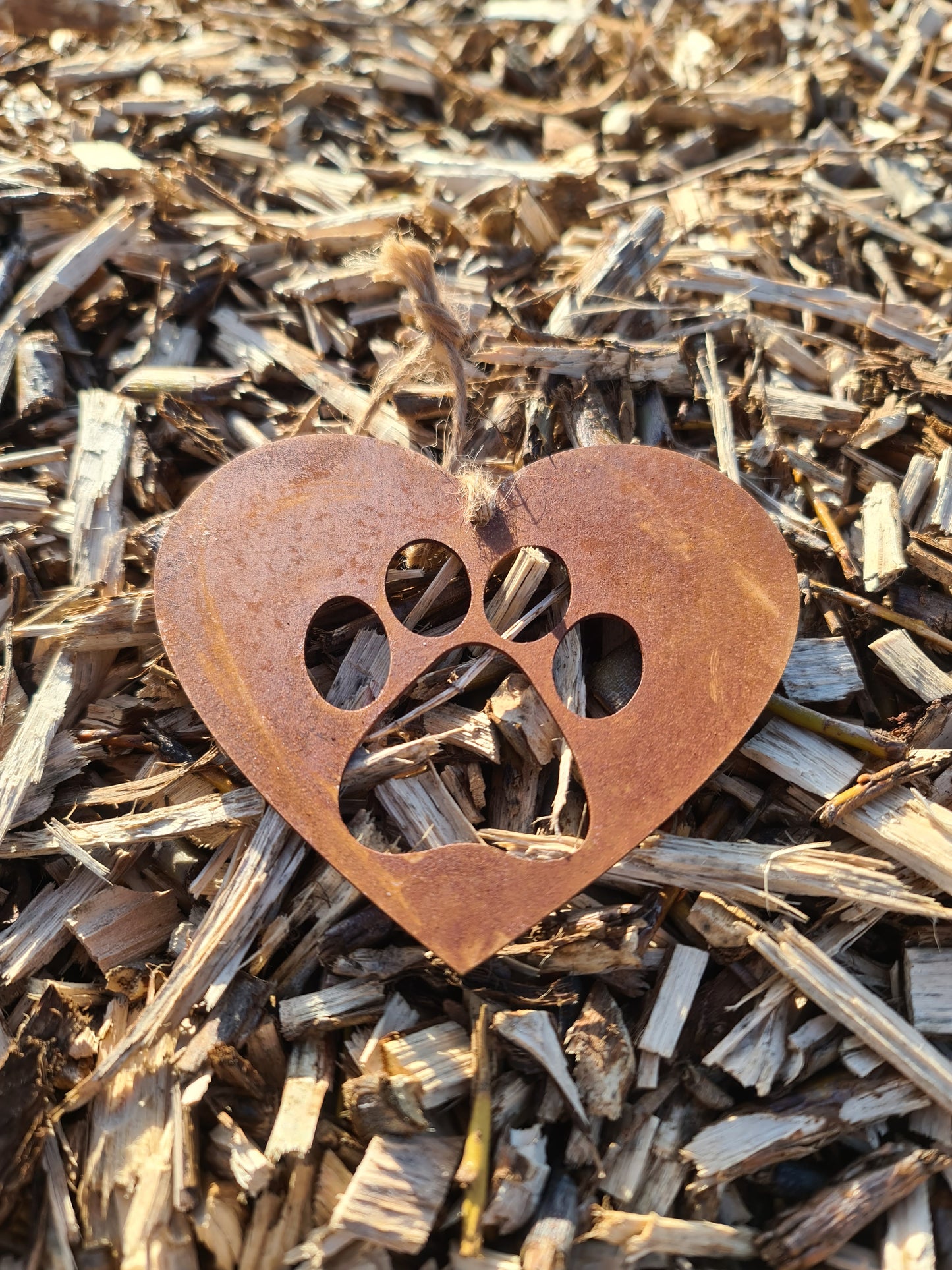 This is a heart-shaped metal decoration featuring a dog's paw print cut-out. Crafted with a rustic finish, this piece makes a thoughtful gift for dog lovers or a charming addition to any home or garden decor, celebrating the bond with a beloved pet.