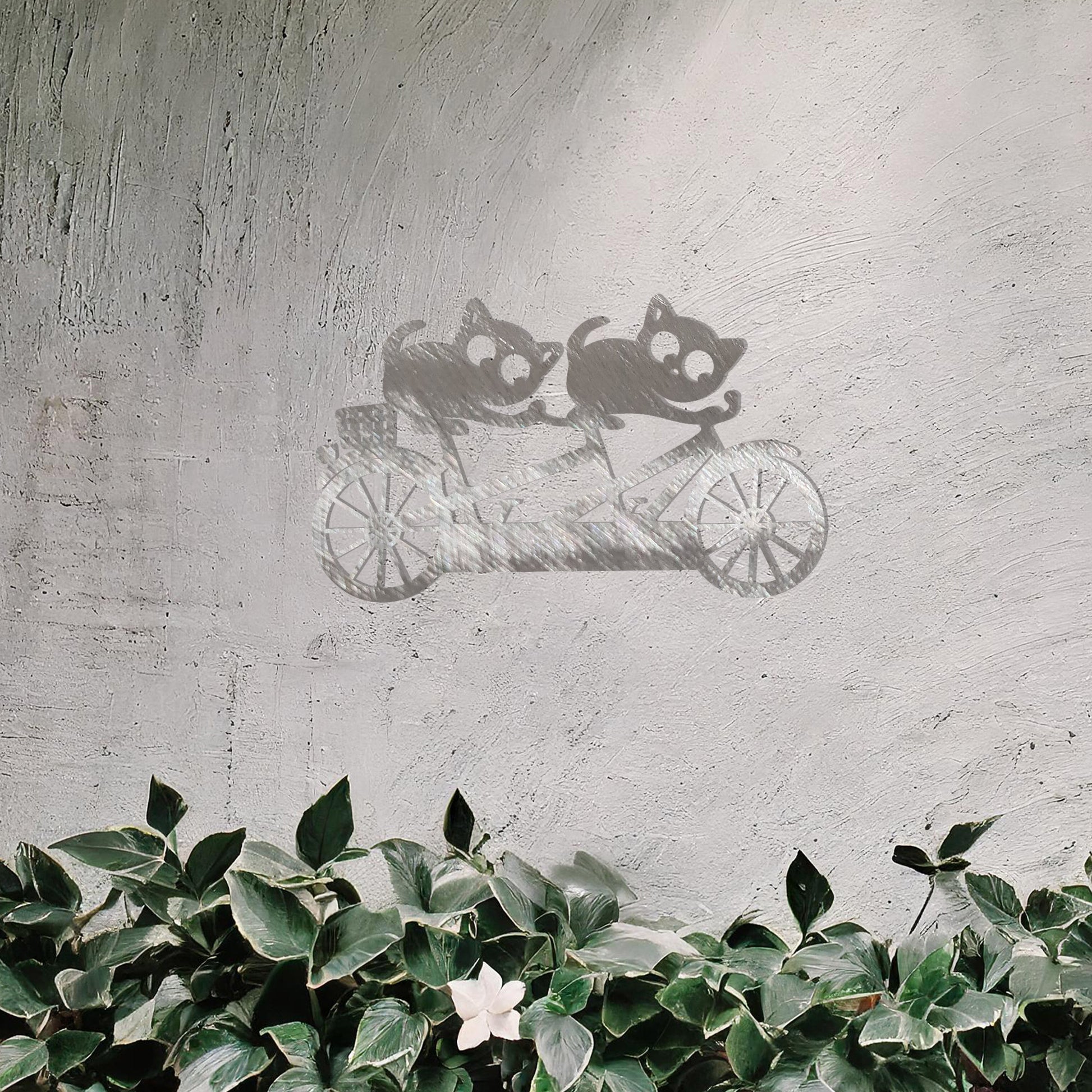 A charming metal wall art design depicting two playful cats riding a tandem bicycle, capturing a whimsical and fun moment with intricate details of the bike and expressive cat figures.
