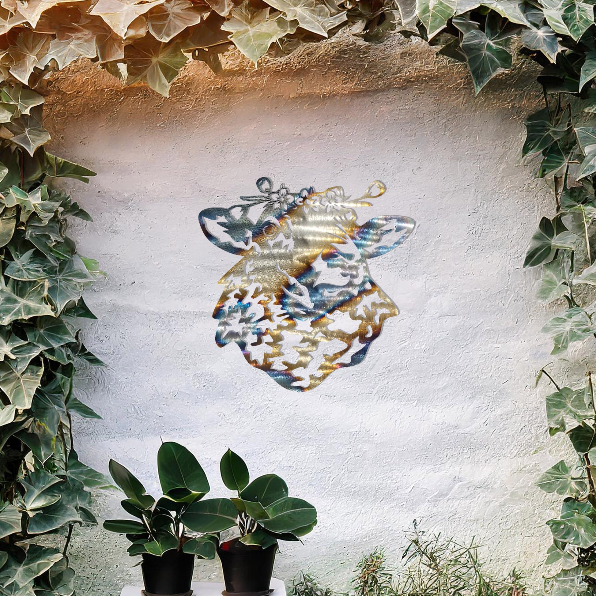 A metal wall art piece depicting a sheep adorned with a floral crown, exuding rustic charm and elegance. This intricate design brings a touch of countryside serenity to any modern or natural setting, complemented by its leafy surroundings.