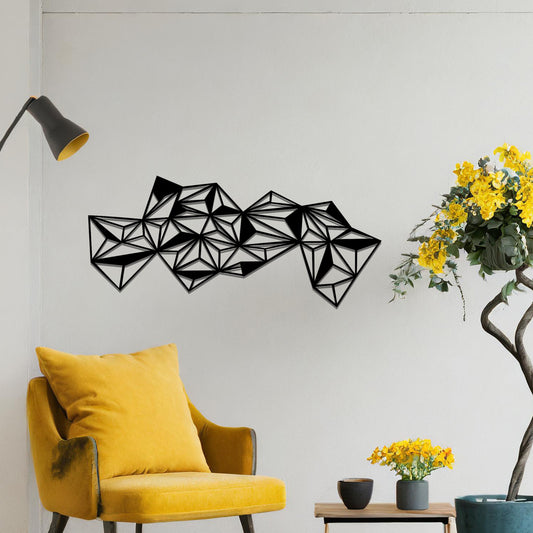 Metal wall art featuring an abstract geometric design with multiple interconnected triangular shapes, creating a dynamic, faceted pattern. The art is placed on a neutral wall within a modern room, complementing the vibrant decor with plants and furniture.