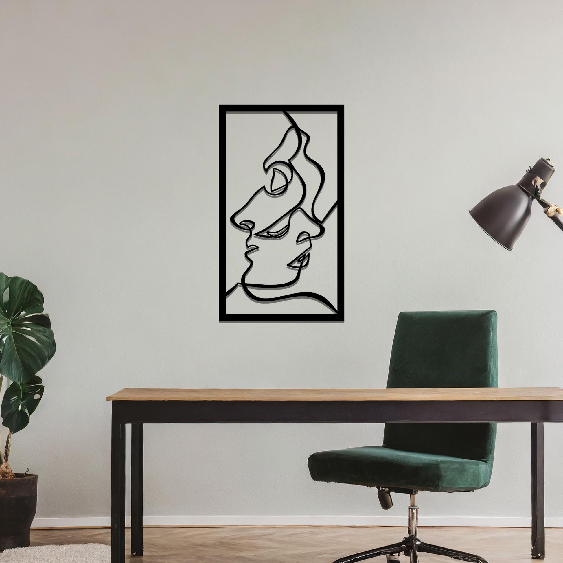 Metal wall art featuring an abstract design of two faces in profile, formed with flowing lines. The art is placed on a neutral wall within a modern office setting, contributing to a stylish and contemporary atmosphere.