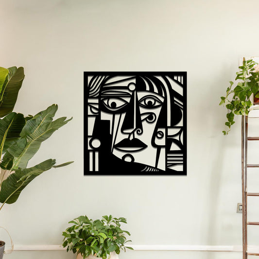 Geometric abstract face design cut from metal. The face features bold lines, sharp angles, and circular elements, creating a unique artistic representation. The art is displayed on a neutral wall in a modern room setting.