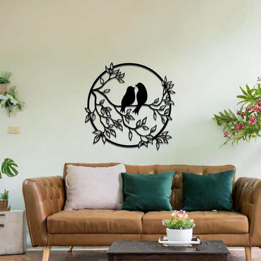 Metal wall art featuring a circular design with two birds perched on a branch surrounded by intricate leaves, adding a charming focal point to a beautifully styled living space.