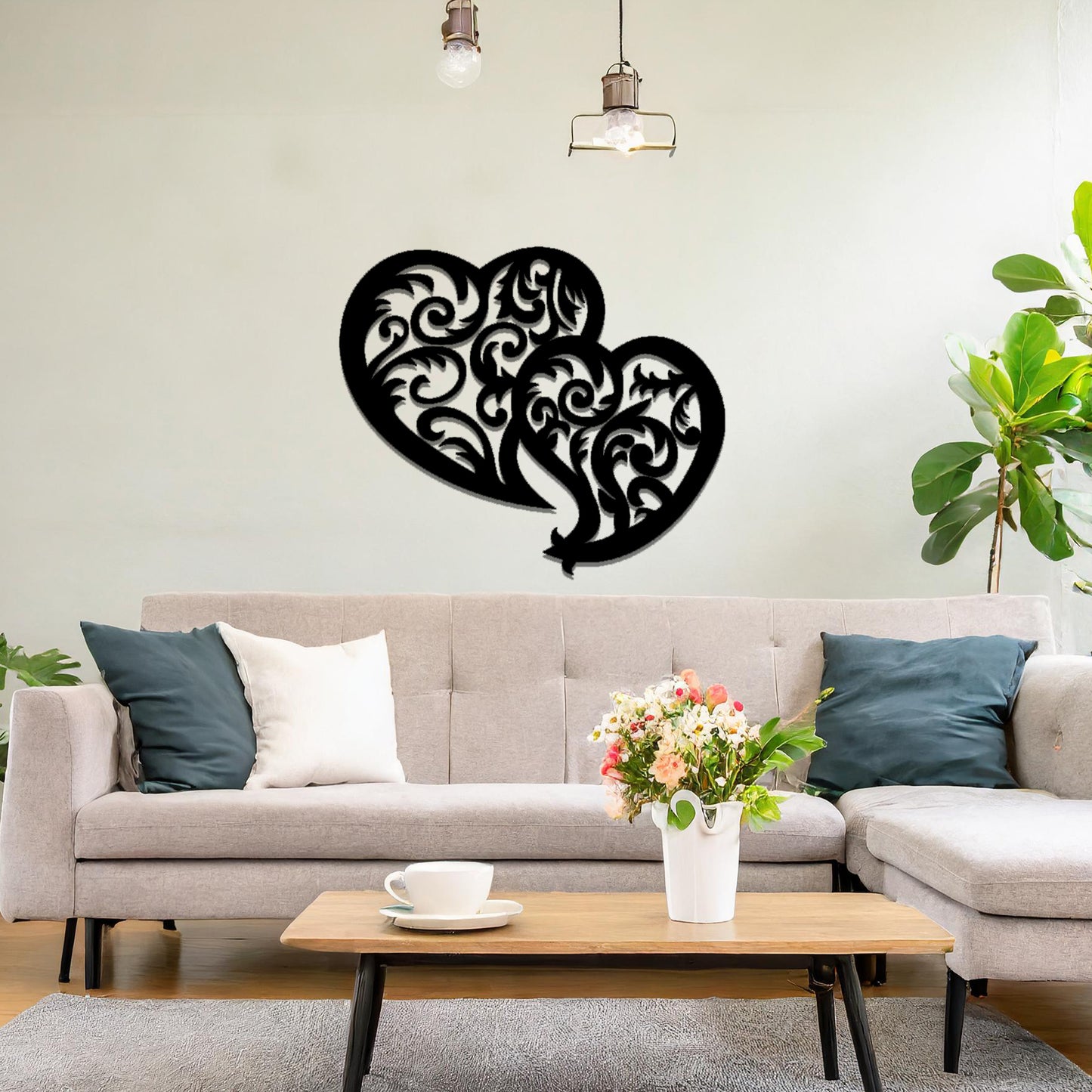 Metal wall art featuring a pair of intricately designed hearts with swirling patterns, mounted on a neutral wall within modern room decor. The elegant detailing creates a romantic and artistic focal point, adding a touch of love to the space.