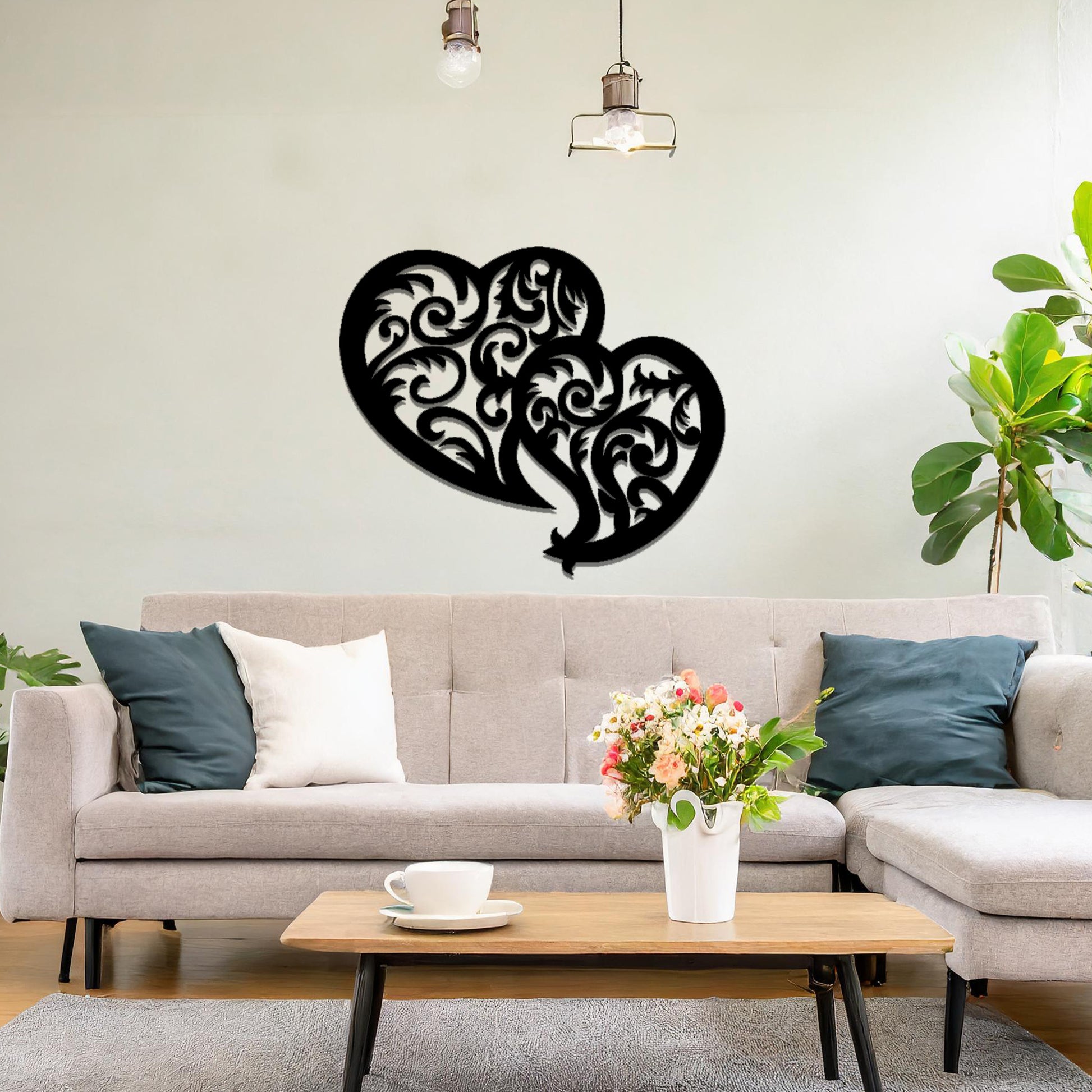 Metal wall art featuring a pair of intricately designed hearts with swirling patterns, mounted on a neutral wall within modern room decor. The elegant detailing creates a romantic and artistic focal point, adding a touch of love to the space.