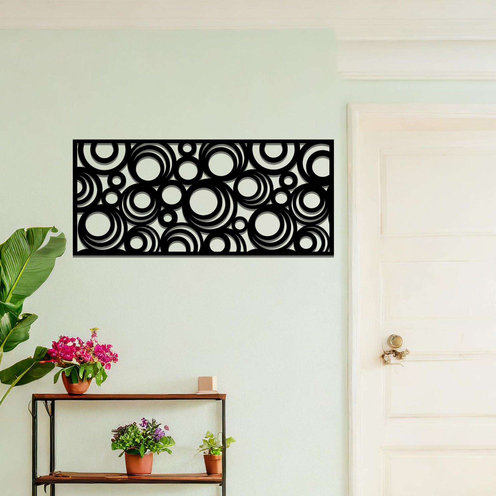 Metal wall art featuring an intricate pattern of overlapping circles in various sizes. The design is set against a neutral wall in a modern living room space, adding a touch of contemporary elegance to the decor.