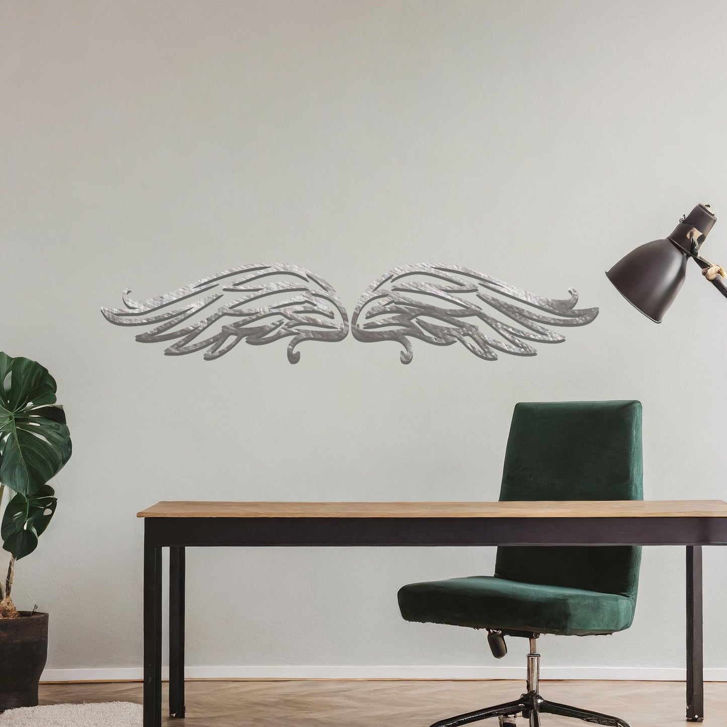A striking metal wall art design of intricately detailed wings, symmetrically positioned with elegant feather-like lines. The artwork is displayed on a neutral wall within a modern decor setting, adding a touch of sophistication.