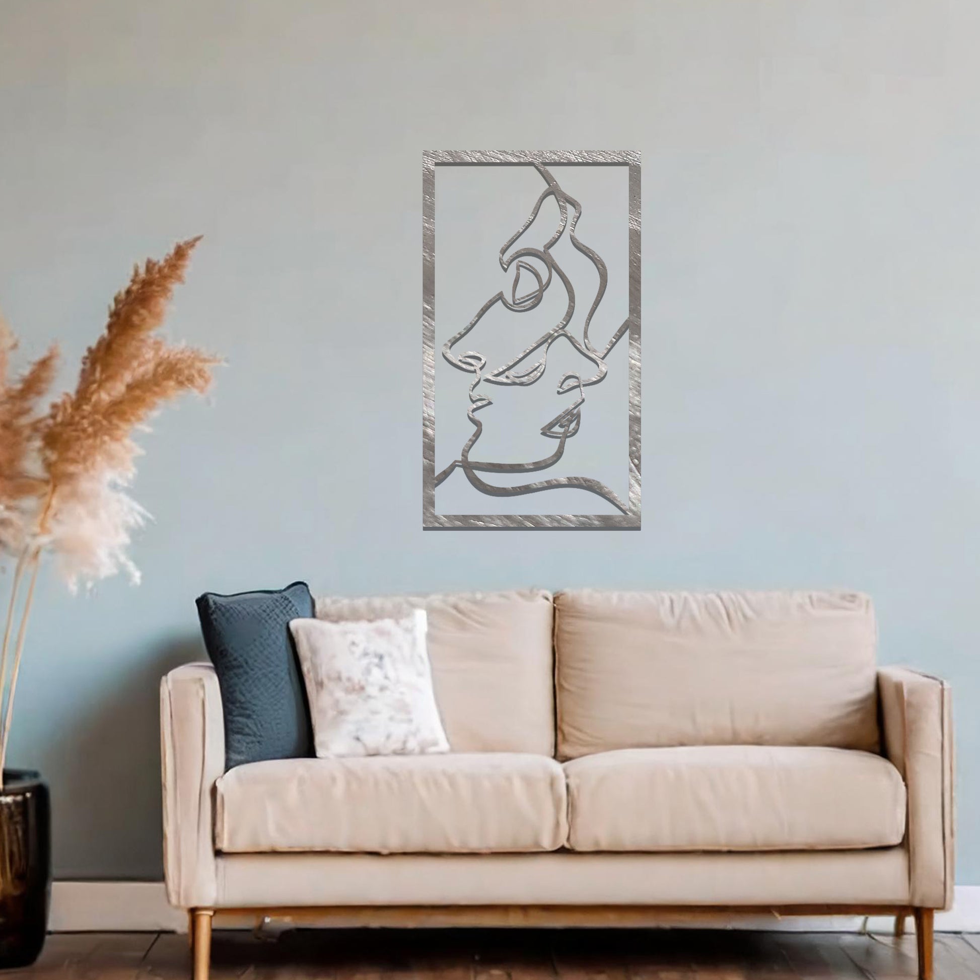 Metal wall art featuring an abstract design of two faces in profile, formed with flowing lines. The art is placed on a neutral wall within a modern office setting, contributing to a stylish and contemporary atmosphere.