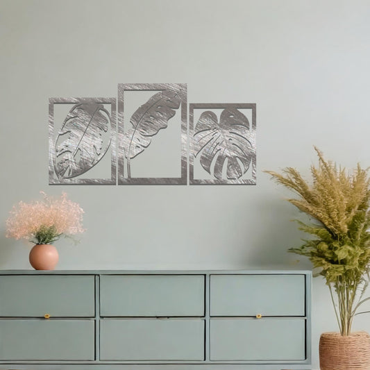 A metal wall art design featuring three leaf patterns, each in its own rectangular frame. The art is displayed on a neutral wall within a modern office space, enhancing the environment with its natural and minimalist appeal.