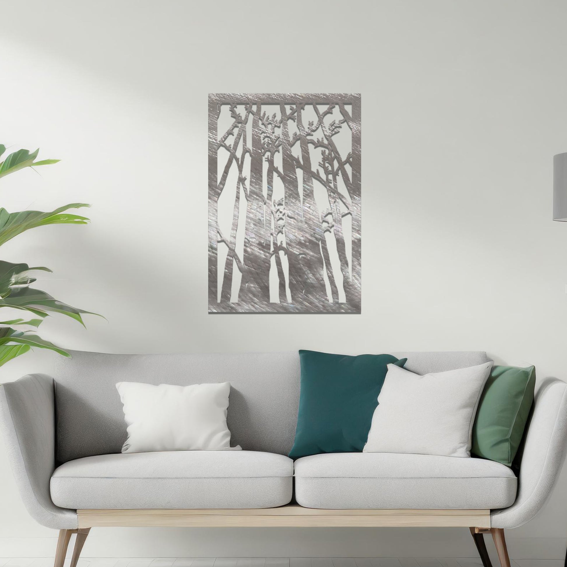 Metal wall art featuring a rectangular design of tall trees with bare branches, showcasing intricate details, displayed on a neutral wall within modern decor.
