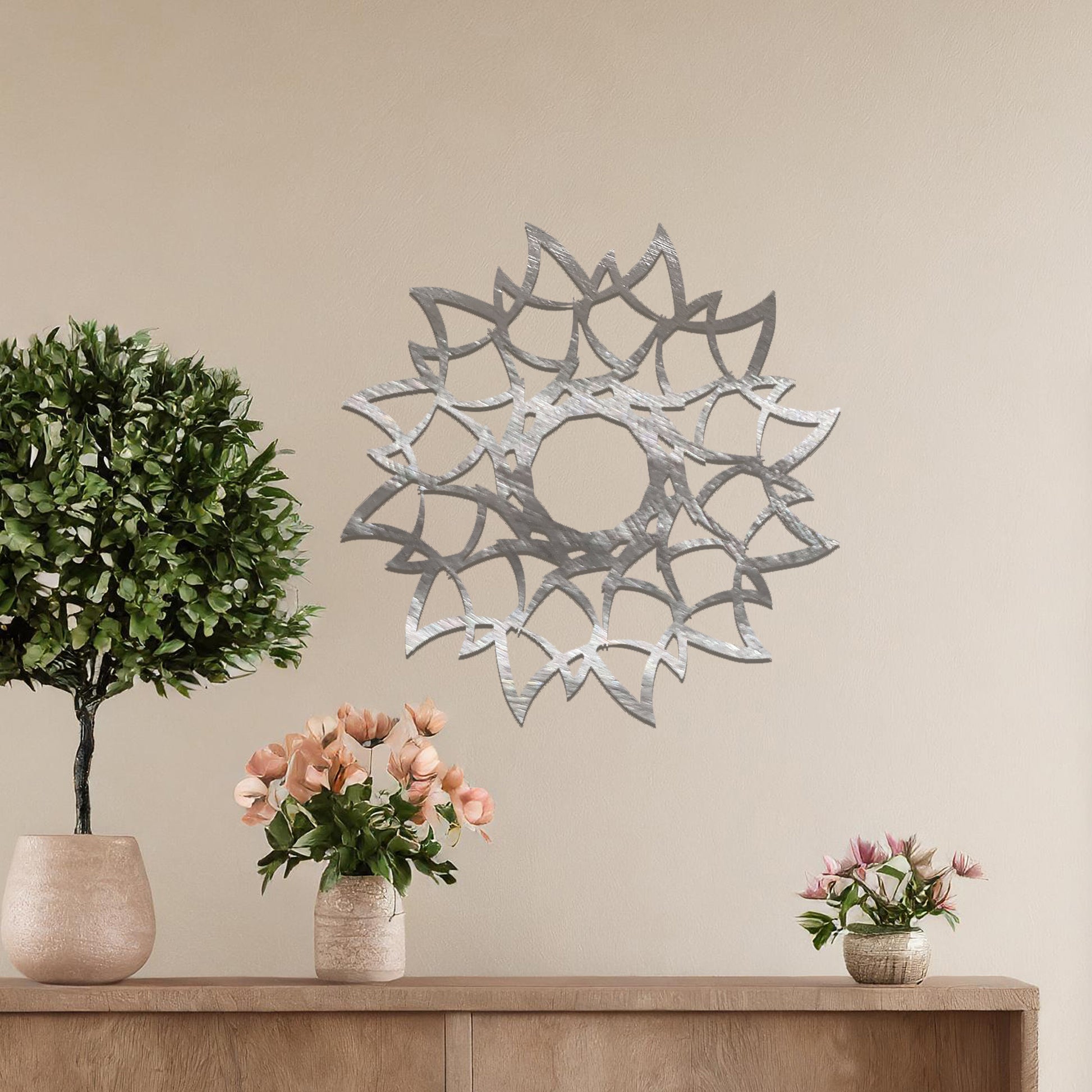 Metal wall art featuring a circular floral-inspired design with layered petal-like patterns, crafted with precise laser-cut detailing, displayed on a neutral wall within modern decor.