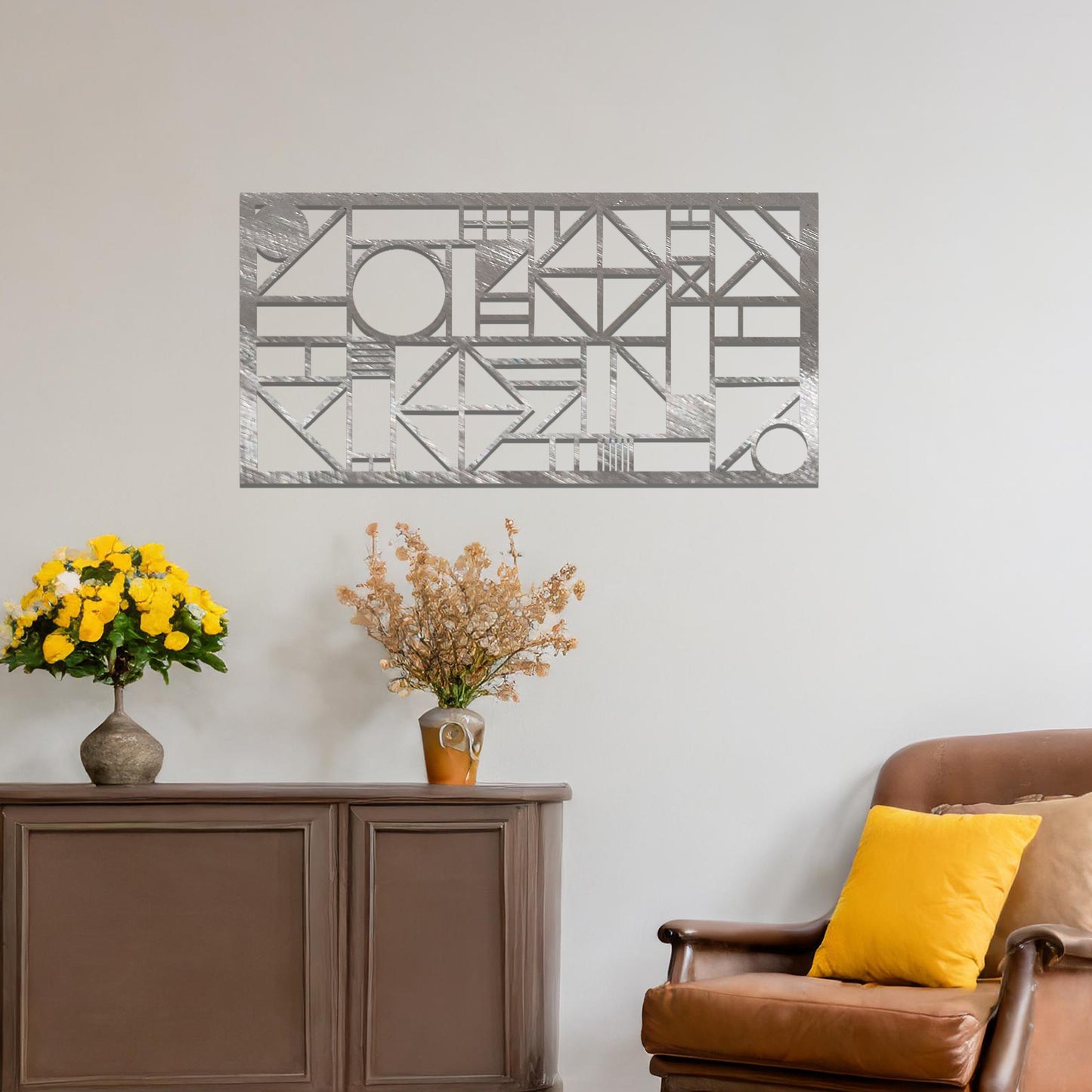 Metal wall art with a geometric design, featuring various abstract shapes, lines, and angles arranged in a structured composition. The art is placed on a neutral wall within modern room decor, adding an artistic touch to the space.