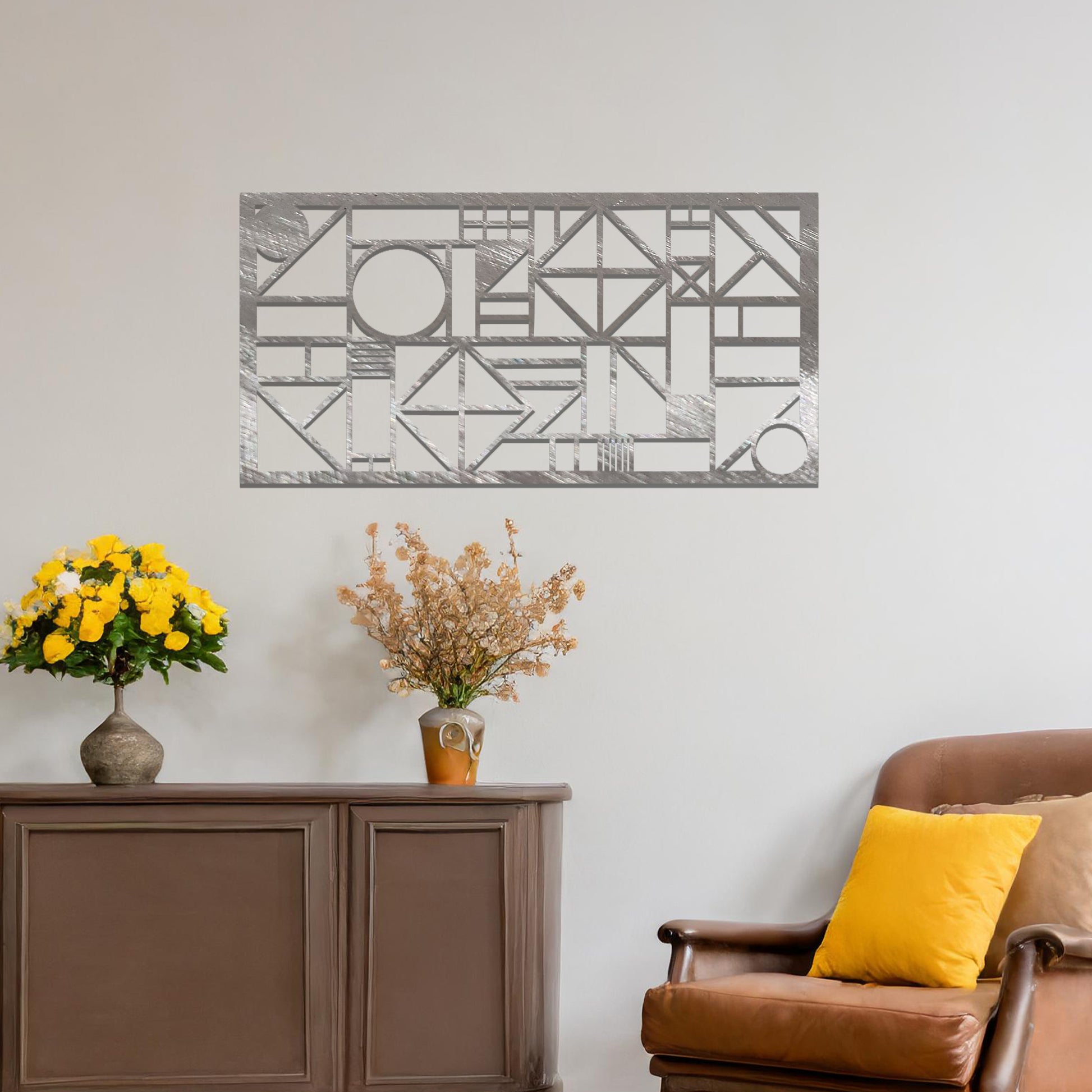 Metal wall art with a geometric design, featuring various abstract shapes, lines, and angles arranged in a structured composition. The art is placed on a neutral wall within modern room decor, adding an artistic touch to the space.