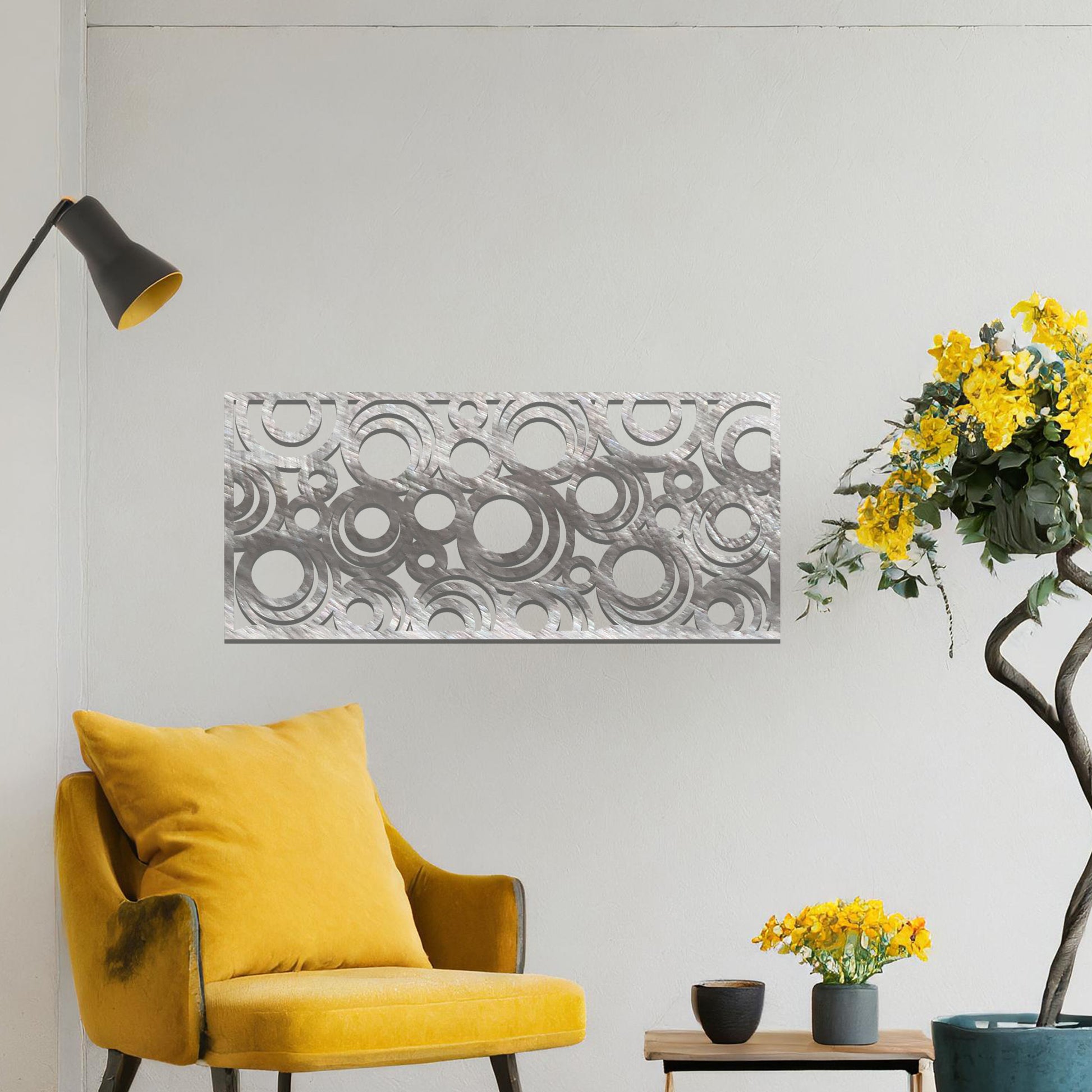 Metal wall art featuring an intricate pattern of overlapping circles in various sizes. The design is set against a neutral wall in a modern living room space, adding a touch of contemporary elegance to the decor.