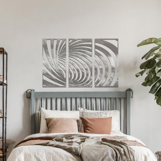 Metal wall art featuring a three-panel design with swirling, spiral-inspired patterns, crafted with precise laser-cut detailing, displayed on a neutral wall within modern decor.