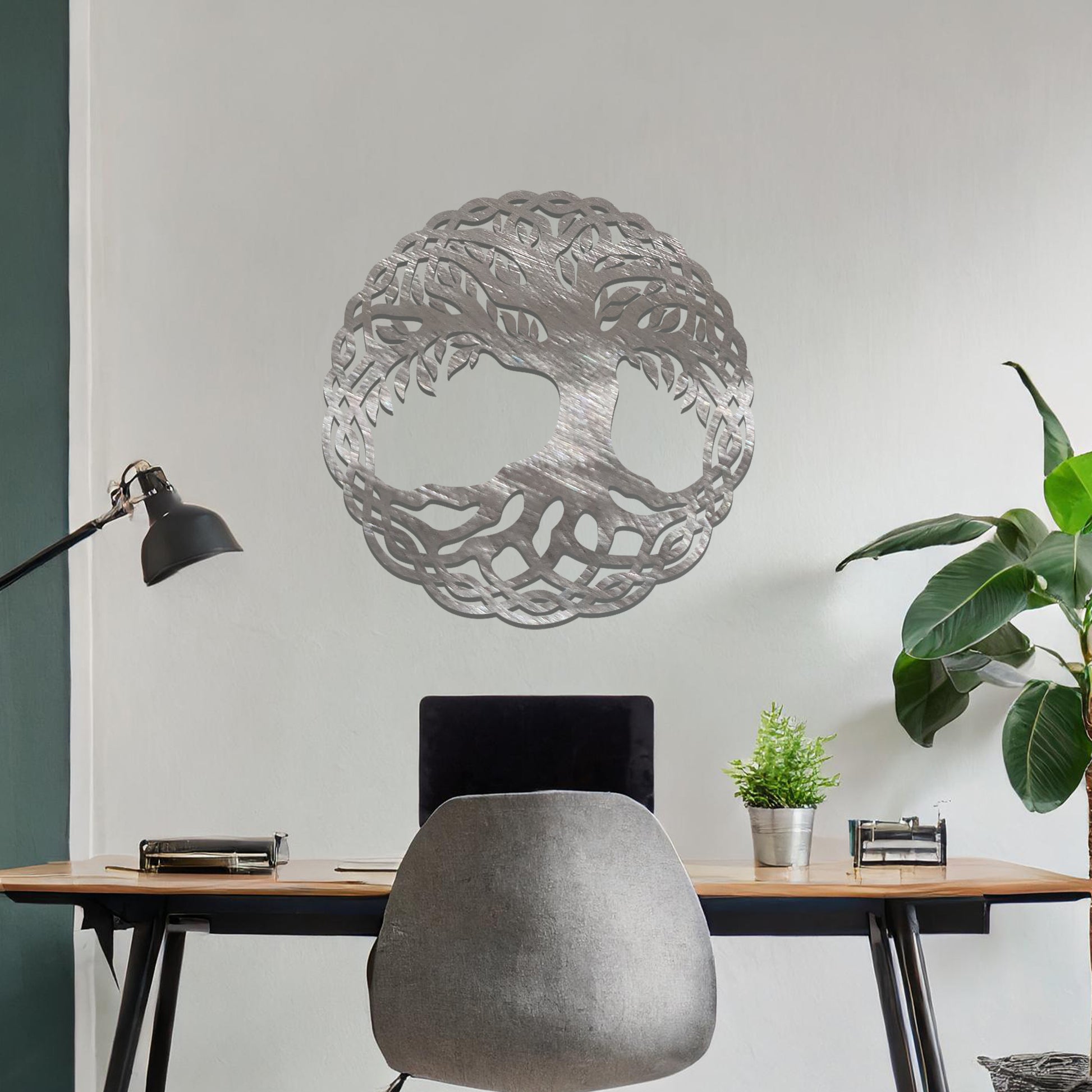 Metal wall art featuring a circular tree of life design with intricate roots and branches enclosed in a detailed border, crafted with precise laser-cut techniques, displayed on a neutral wall within modern decor.