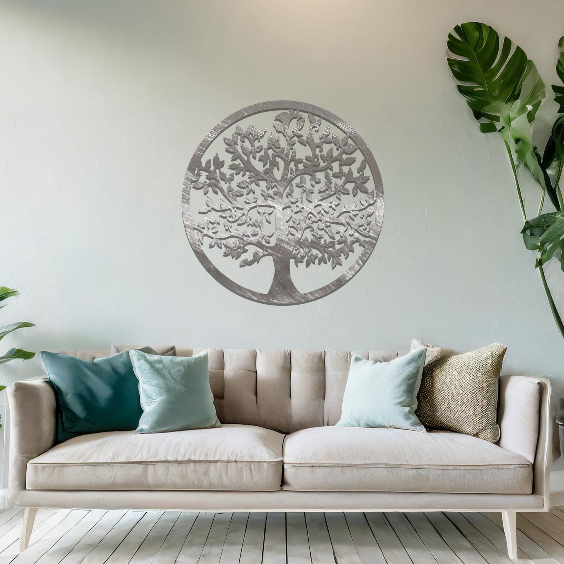 Metal wall art featuring a circular design with a detailed tree of life motif, showcasing intricate branches and leaves, mounted on a neutral wall within modern room decor. The elegant craftsmanship and symbolic design add a touch of sophistication and meaning to the space.