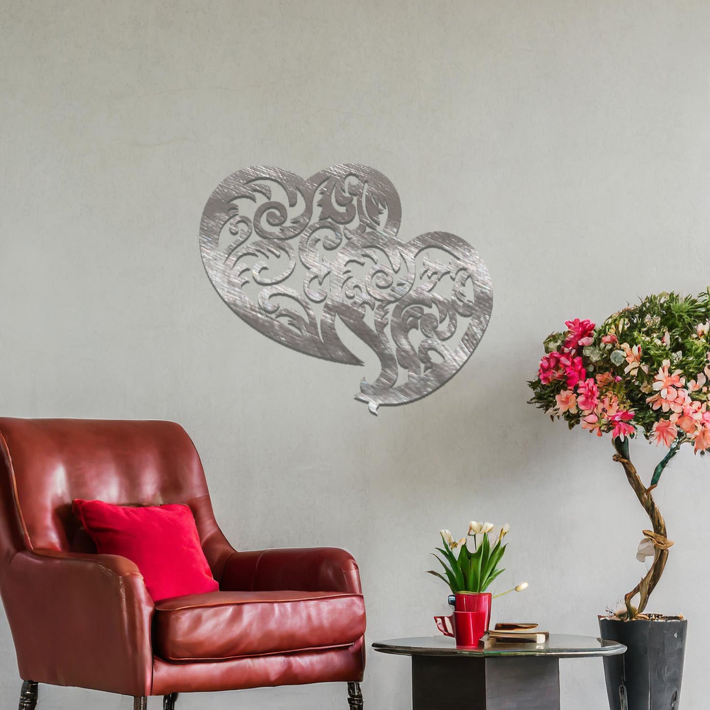 Metal wall art featuring a pair of intricately designed hearts with swirling patterns, mounted on a neutral wall within modern room decor. The elegant detailing creates a romantic and artistic focal point, adding a touch of love to the space.