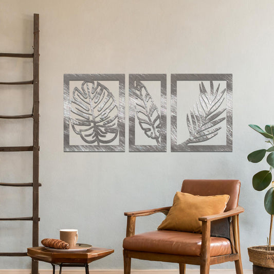 Metal wall art featuring a three-panel design with detailed leaf patterns, mounted on a neutral wall within modern decor. The organic motifs and rust finish create a natural, earthy focal point, enhancing the room's aesthetic.