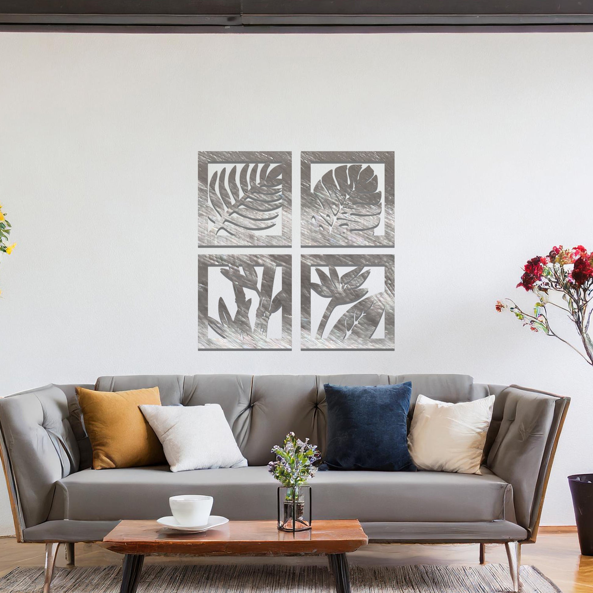 Metal wall art featuring four square panels with intricate leaf designs. The panels showcase detailed plant patterns arranged in a modern layout, mounted on a neutral wall within contemporary room decor, enhancing the room's natural ambiance