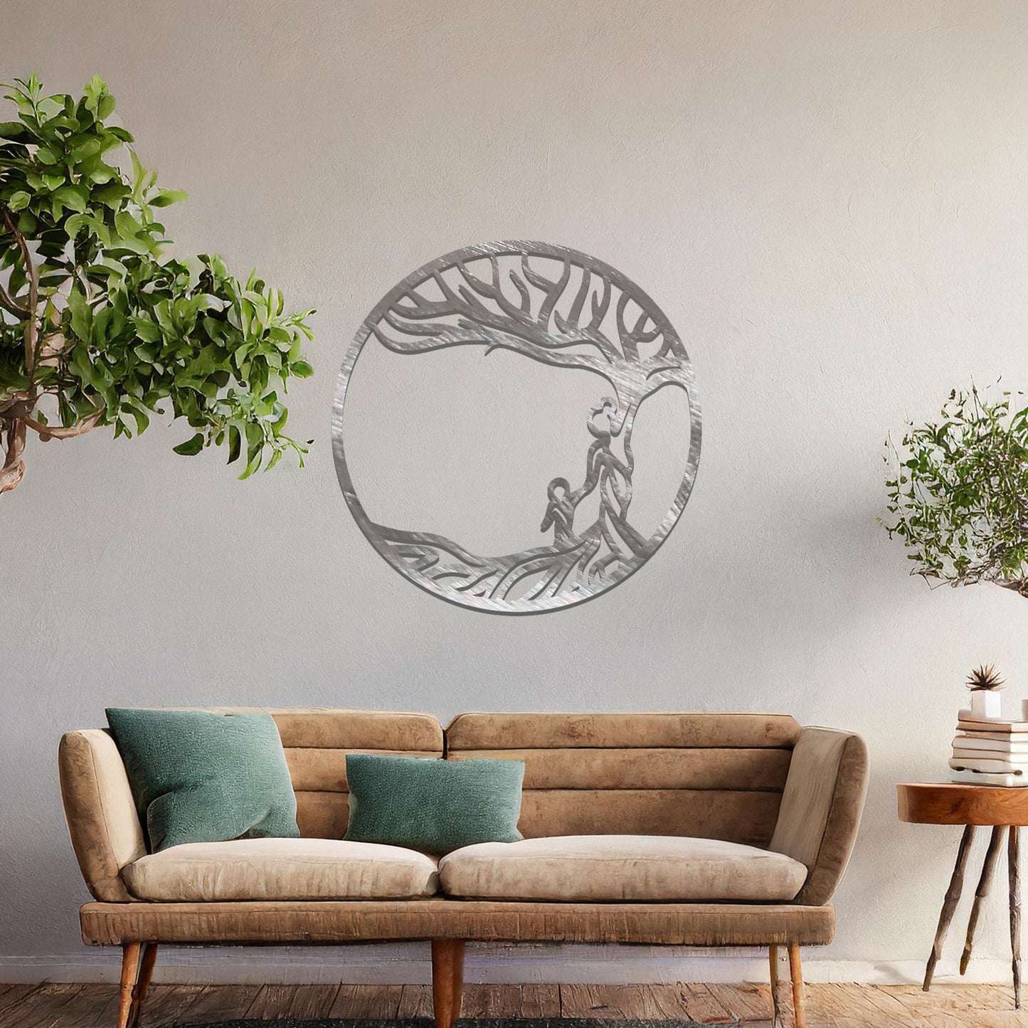 Metal wall art featuring a circular design with a symbolic tree and figures motif, depicting a parent and child under a tree with flowing branches, mounted on a neutral wall within modern room decor. The intricate design evokes warmth and connection, enhancing the aesthetic of the space.