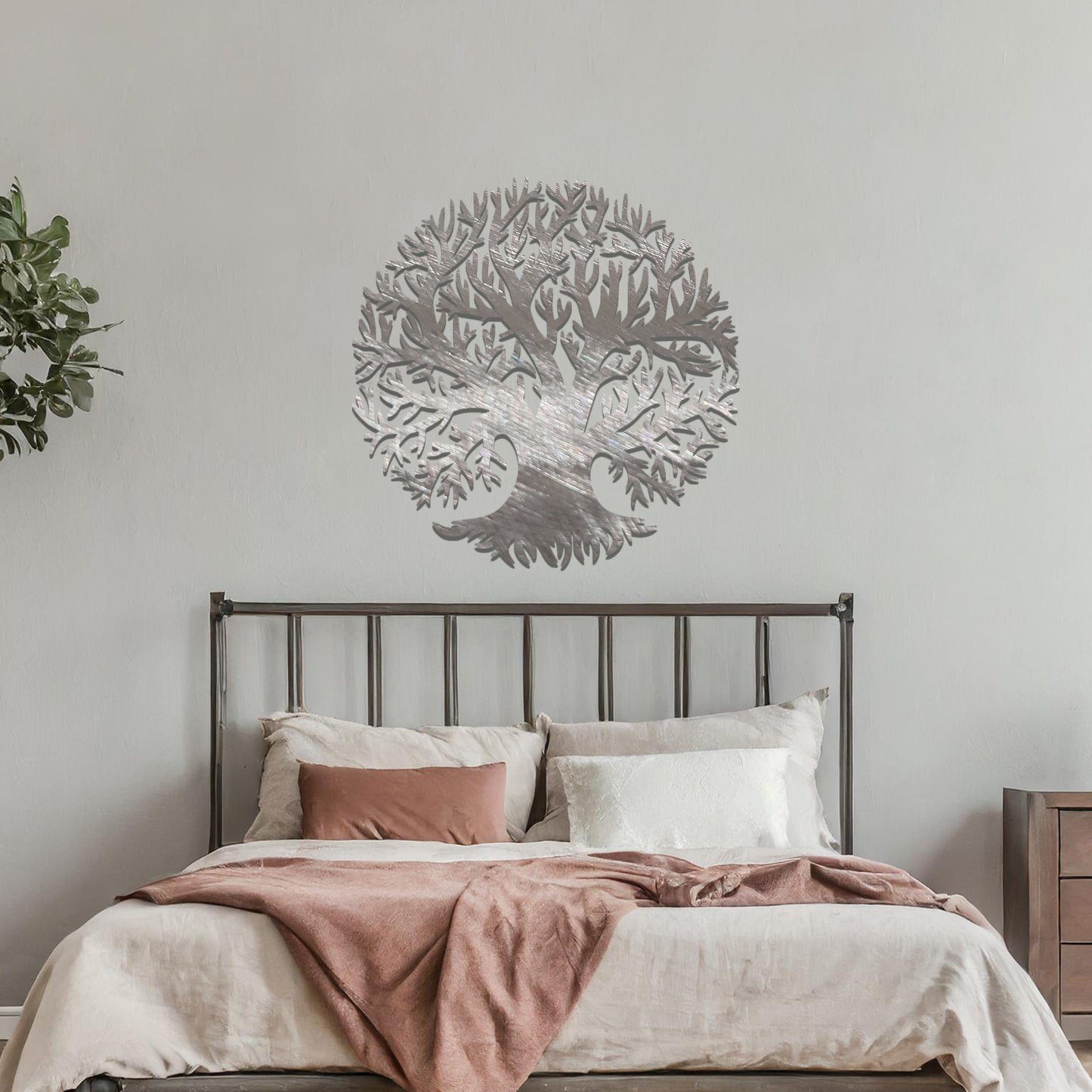 Metal wall art featuring a circular tree design with intricate branches and roots, crafted with precise laser-cut detailing, placed on a neutral wall within modern decor.