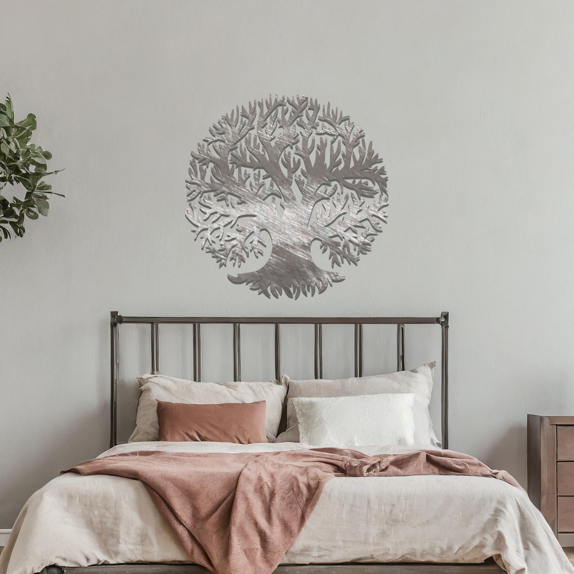 Metal wall art featuring a circular tree design with intricate branches and roots, crafted with precise laser-cut detailing, placed on a neutral wall within modern decor.