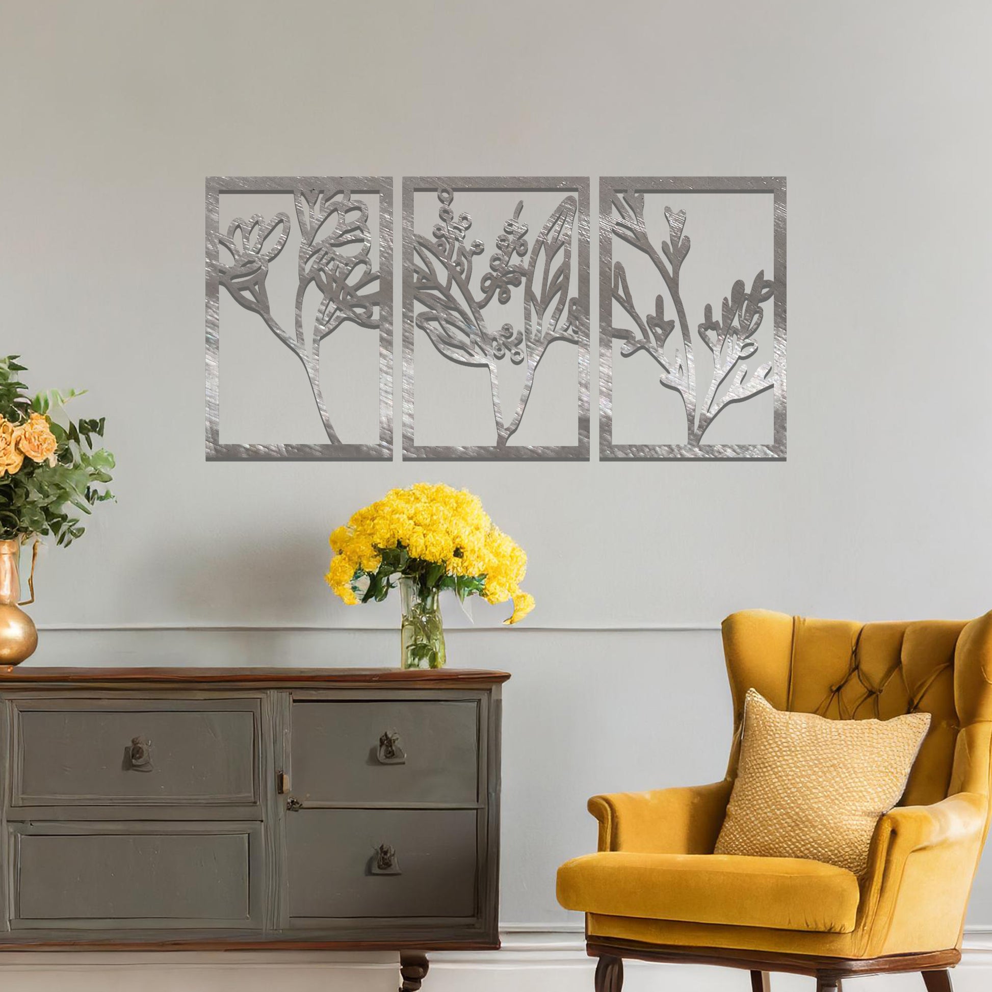 A set of three metal panels featuring intricate botanical designs, with delicate plant shapes in a flowing pattern. The artwork is placed on a neutral wall, enhancing the natural, calming atmosphere of the modern living space.