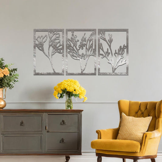 A set of three metal panels featuring intricate botanical designs, with delicate plant shapes in a flowing pattern. The artwork is placed on a neutral wall, enhancing the natural, calming atmosphere of the modern living space.
