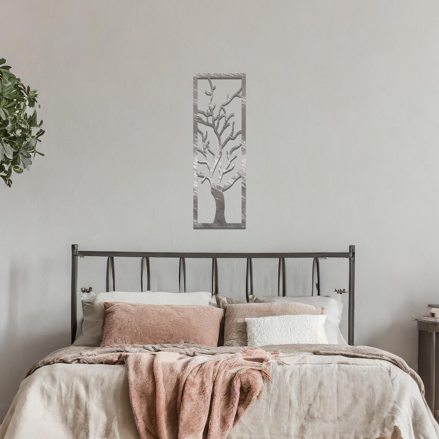 Metal wall art featuring a vertical design of a bare tree with intricate branches, mounted on a neutral wall within elegant room decor. The minimalist silhouette of the tree adds a sophisticated, natural focal point to the space.